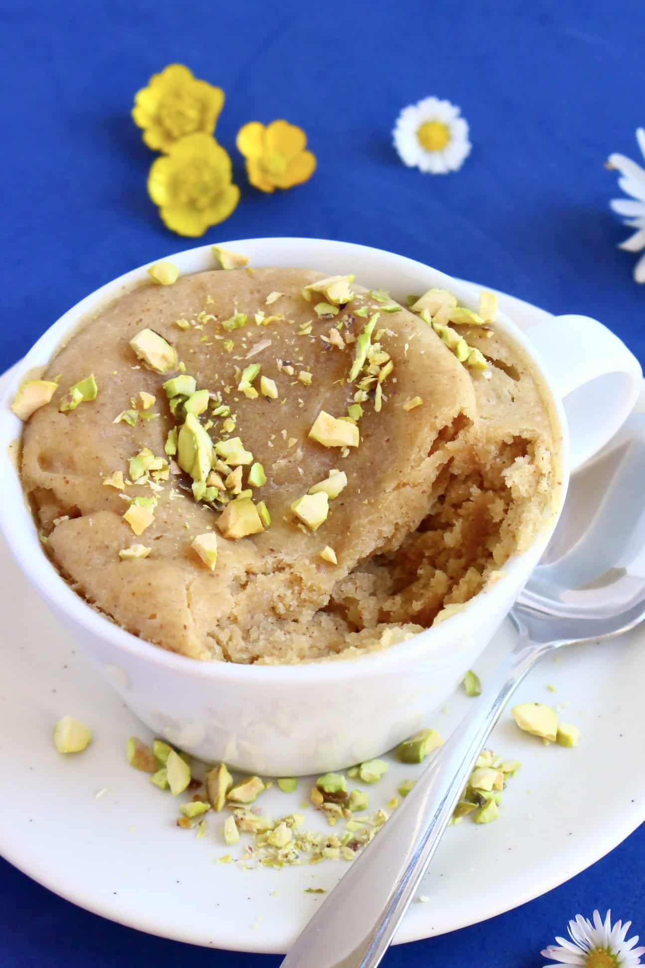 A 3-ingredient vegan Biscoff mug cake in a mug with a mouthful taken out of it