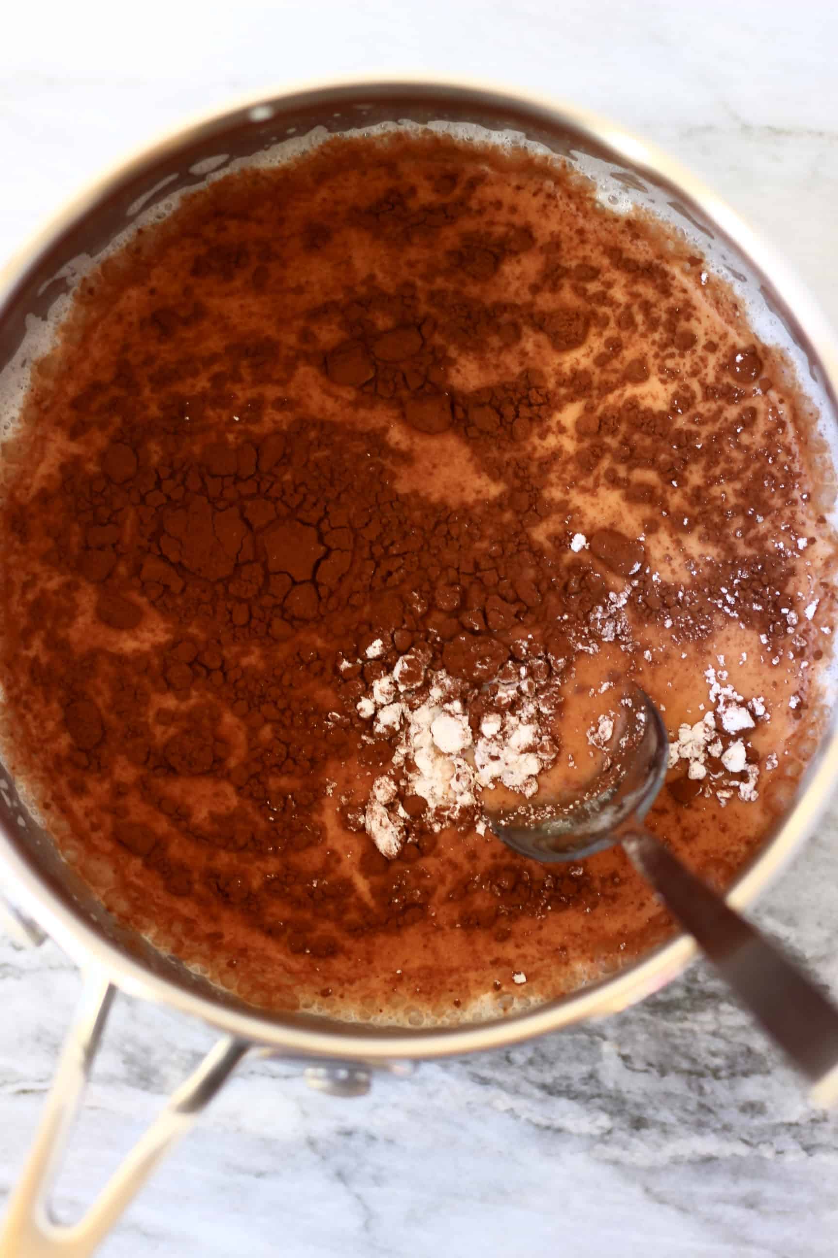 A pan filled with plant-based milk and cocoa powder with a spoon in it