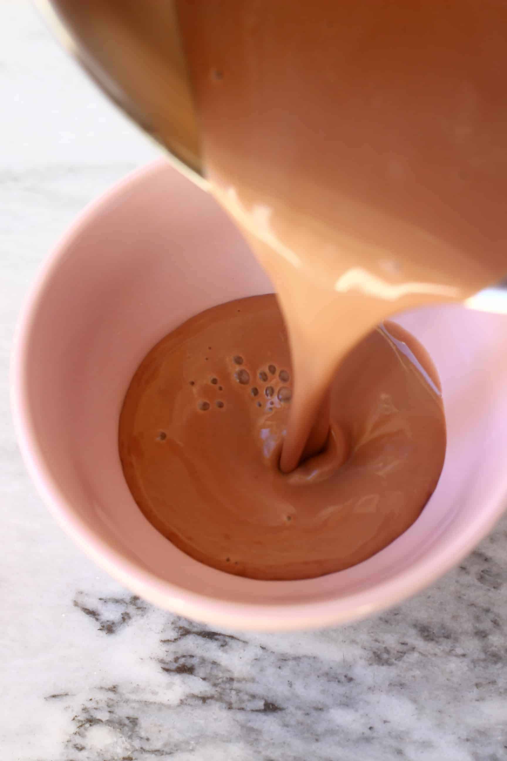 Vegan hot chocolate being poured into a bowl from a pan