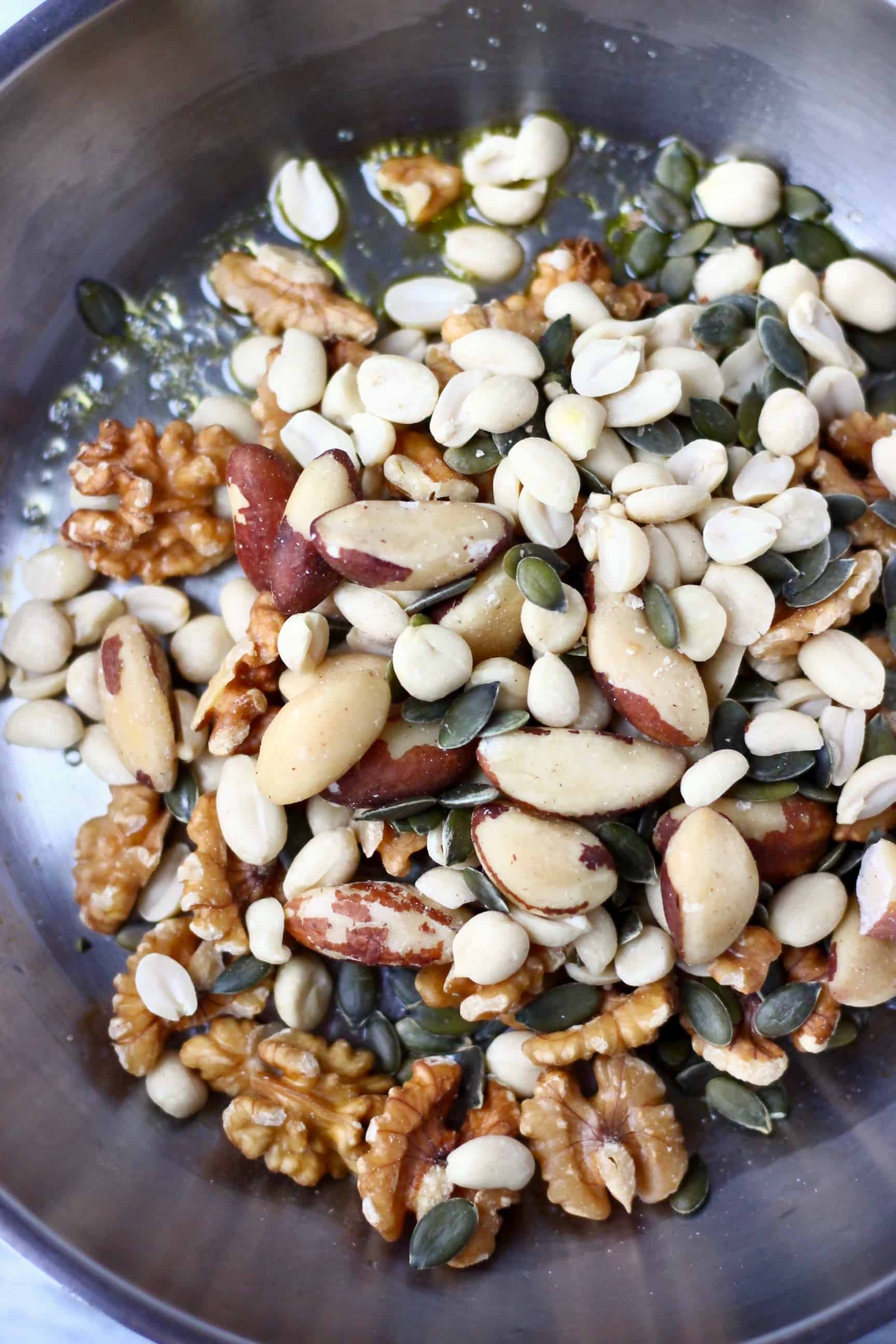 A silver frying pan with nuts and pumpkin seeds inside