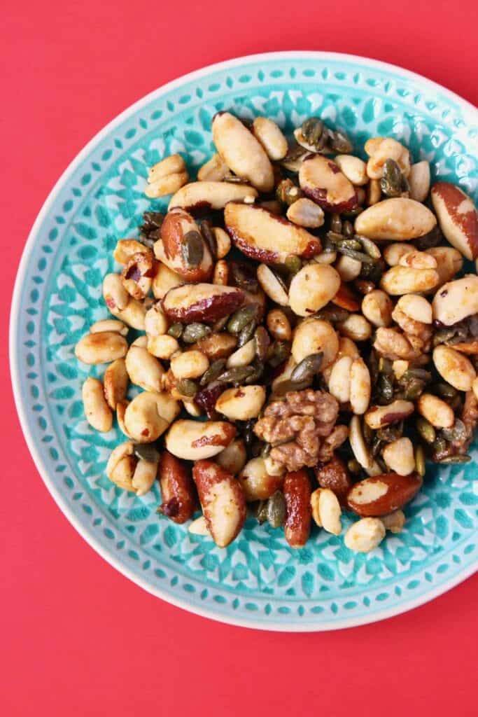 Photo of caramelised nuts on a green plate against a red background