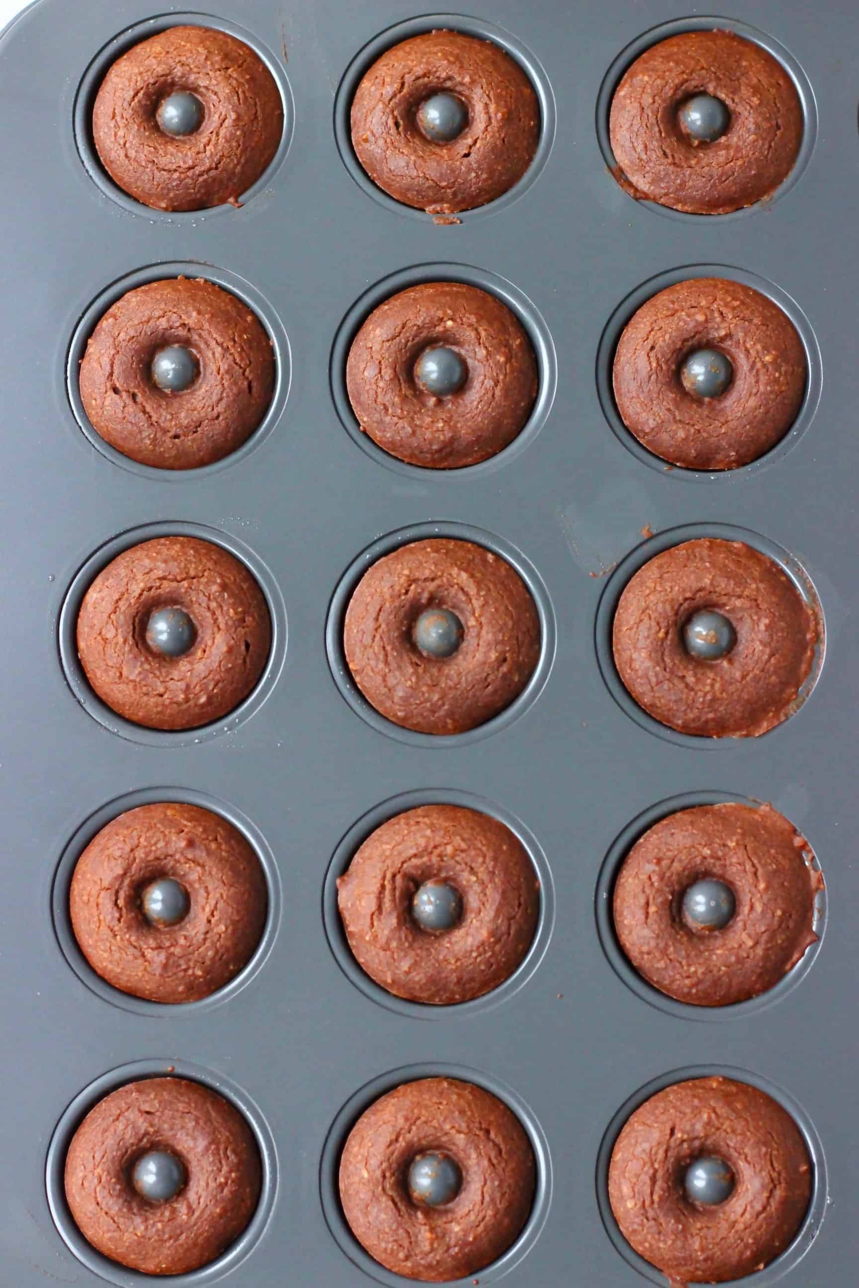 These Vegan Chocolate Baked Donuts are moist and fluffy and covered in a shiny chocolate glaze. A perfect snack or dessert for parties! Egg-free, dairy-free, gluten-free and refined sugar free. #rhiansrecipes #donuts #vegan #glutenfree #dairyfree Cooked chocolate donuts in a mini donut tin