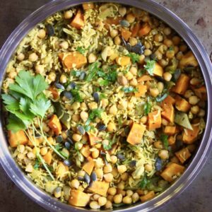 Photo of yellow biryani rice with chopped pumpkin, chickpeas and pumpkin seeds in a silver saucepan