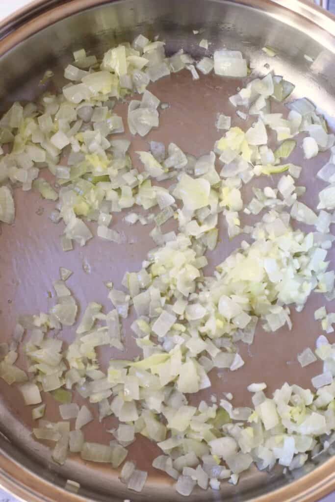 Photo of diced onion being fried in a silver pan