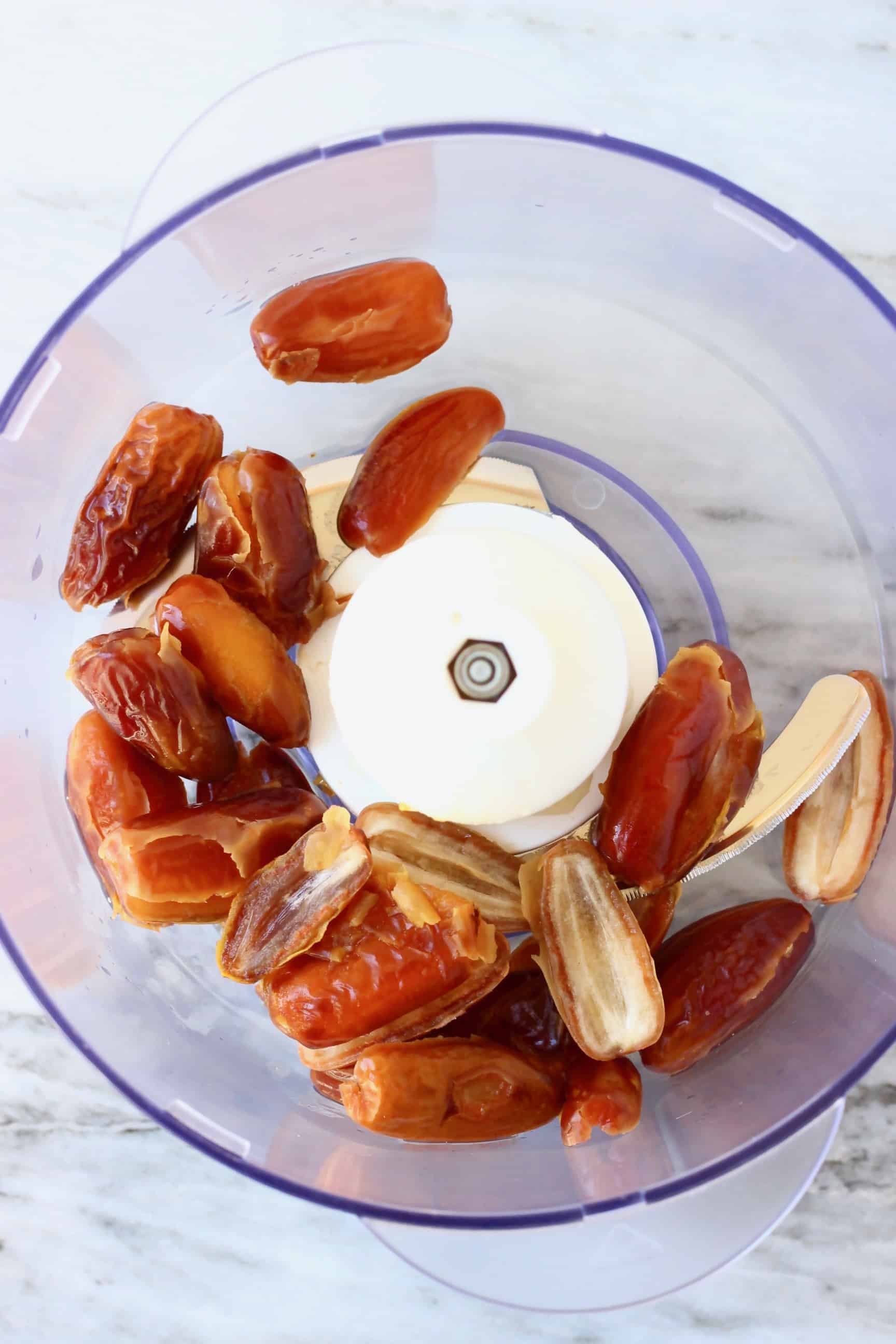 Dates in a food processor against a marble background