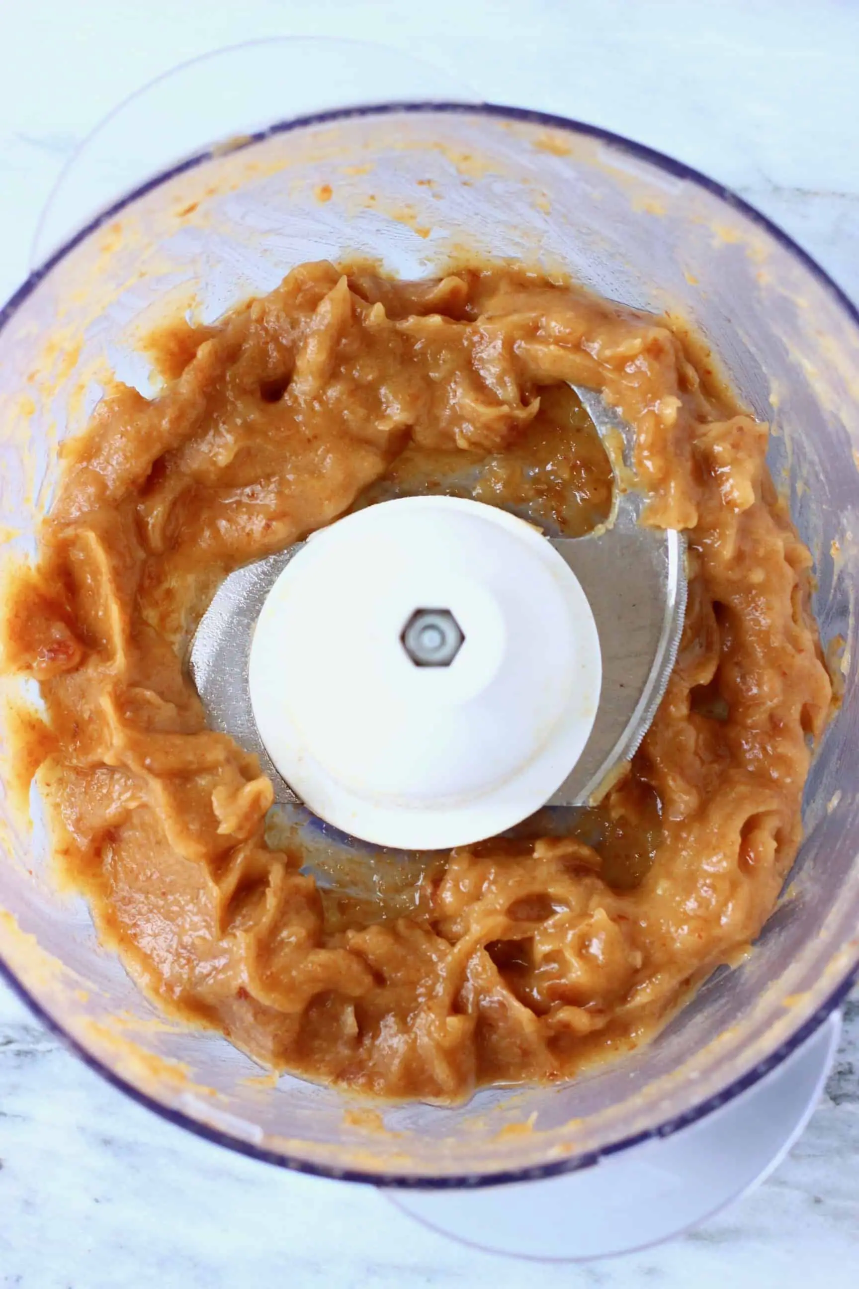 Date paste in a food processor against a marble background