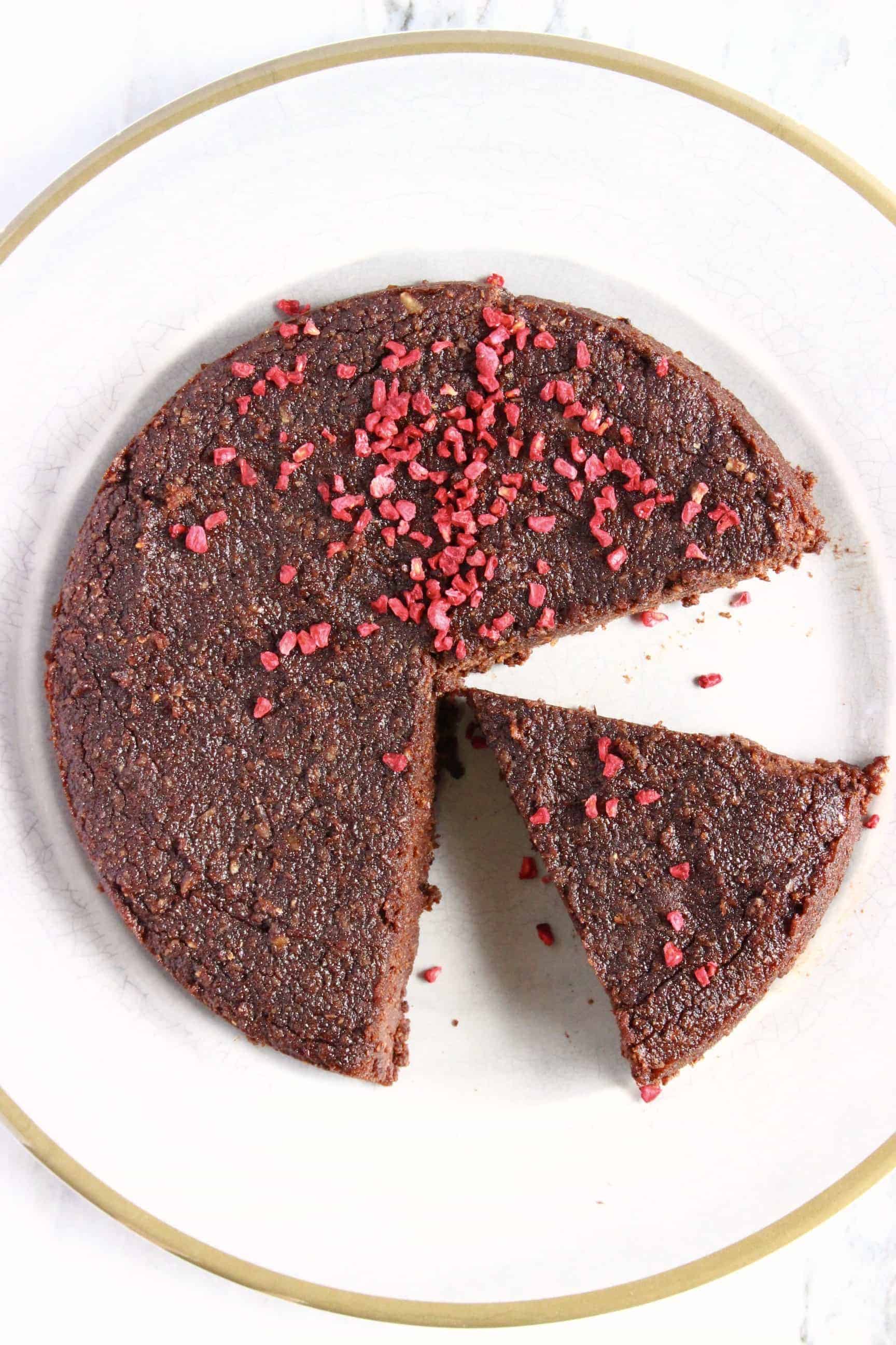 A gluten-free vegan chocolate torte with slices cut out of it on a plate