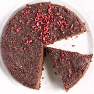 A gluten-free vegan chocolate torte with slices cut out of it on a plate