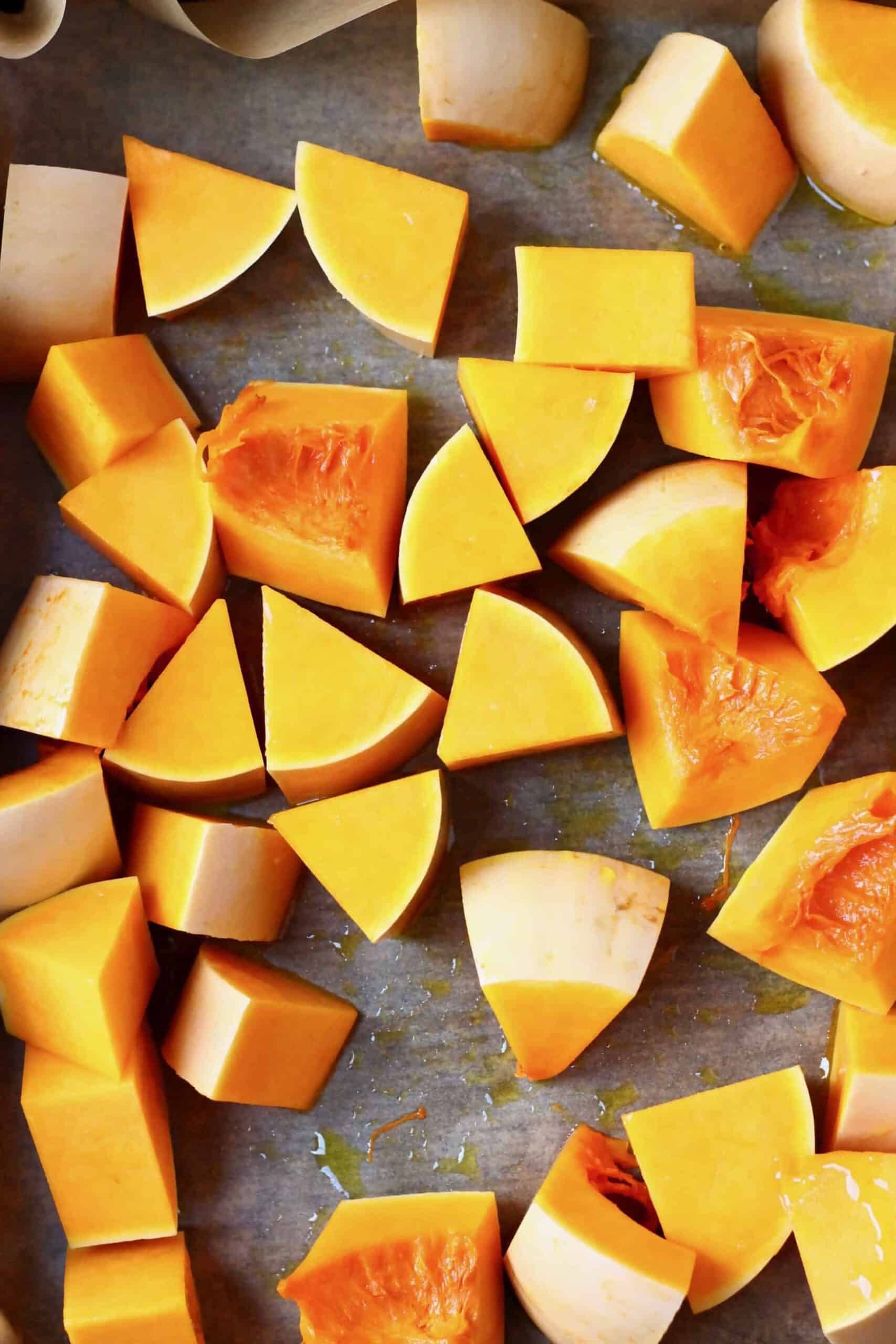 Pieces of pumpkin on a baking tray lined with baking paper