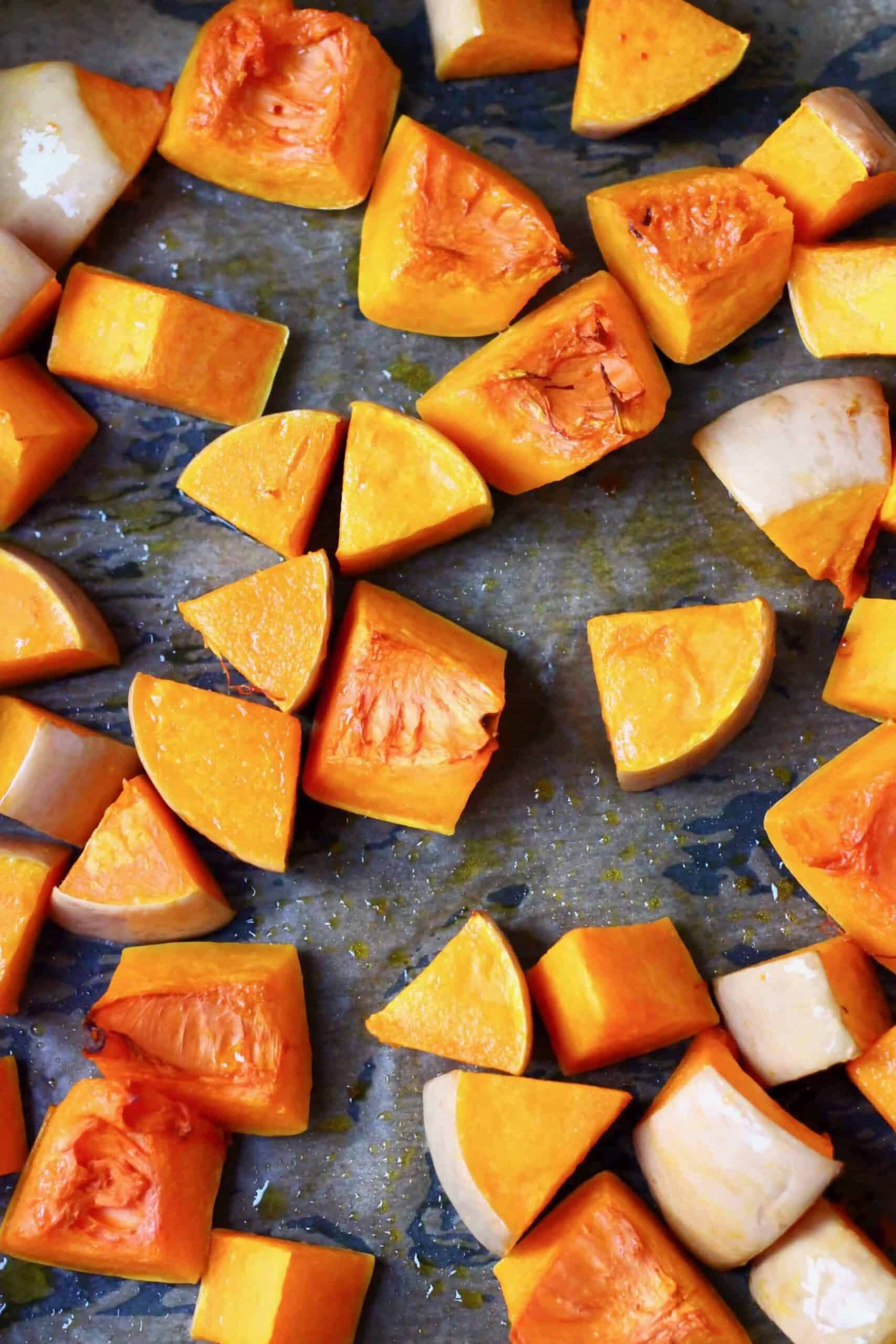 Pieces of roasted pumpkin on a baking tray lined with baking paper