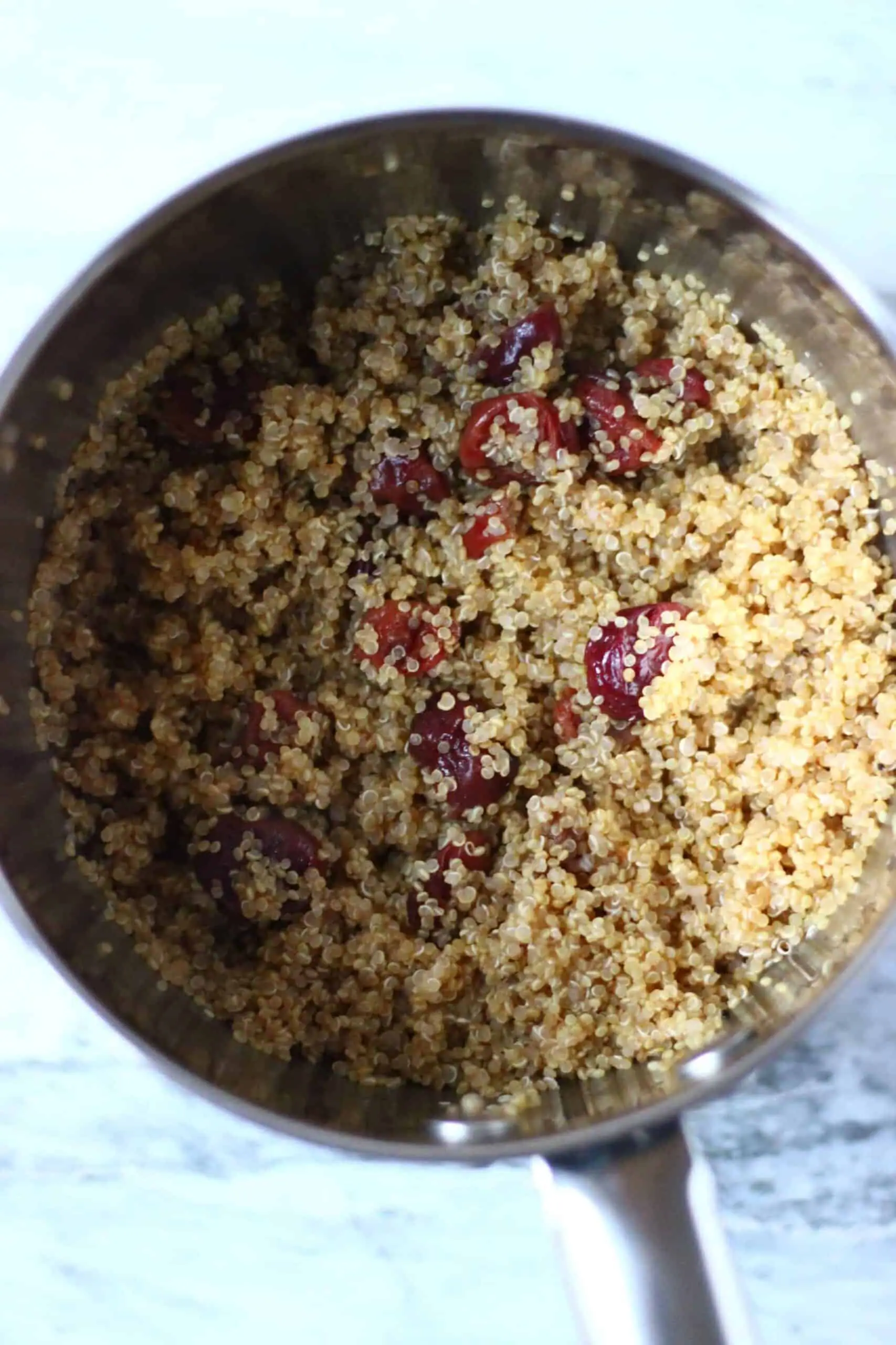 Cooked quinoa and dried cranberries in a pan