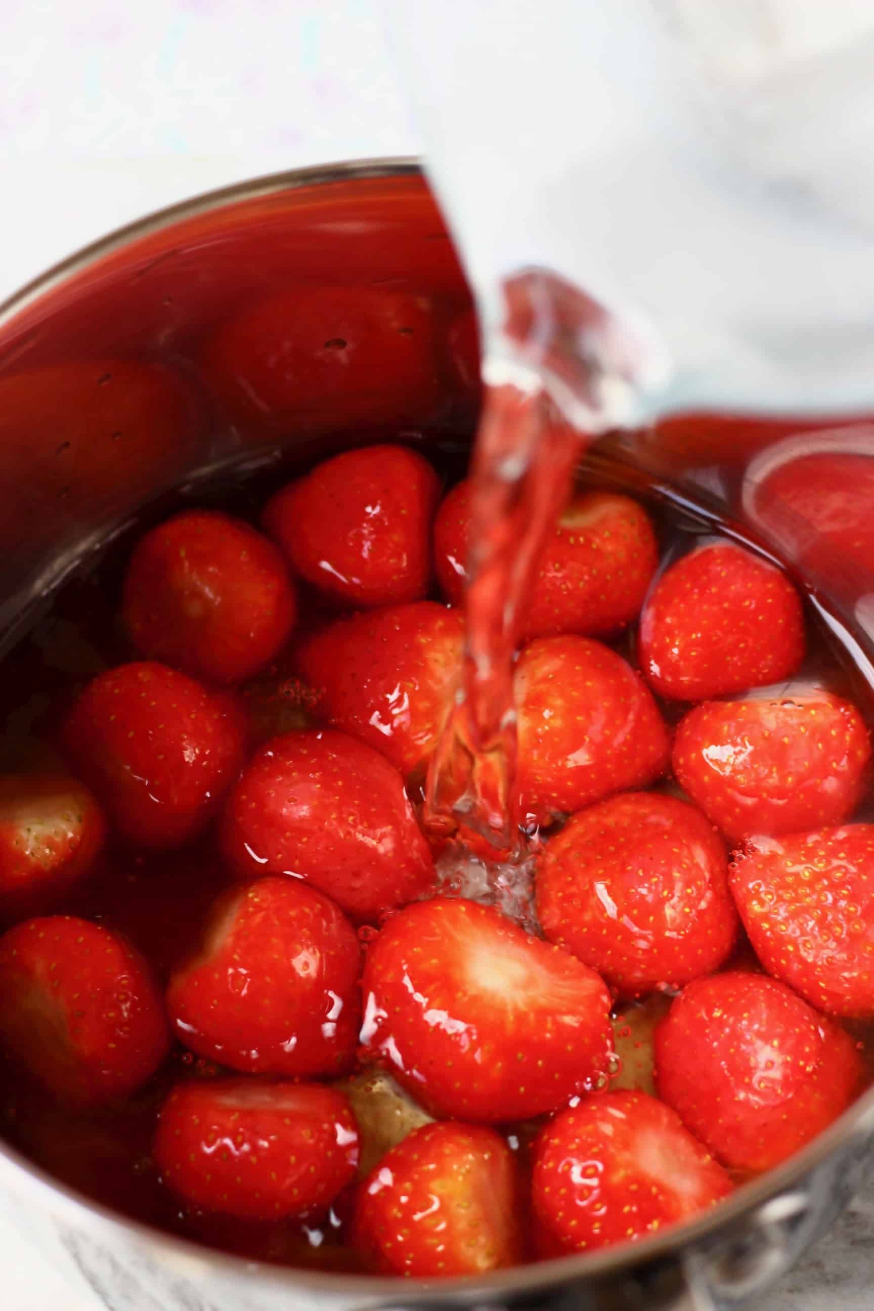 Fresh strawberries in a silver pan with a jug pouring water into it