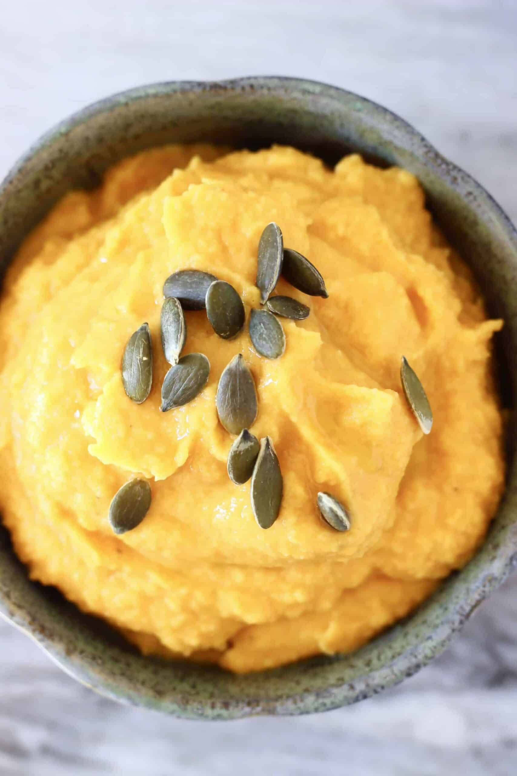 Pumpkin hummus in a bowl topped with pumpkin seeds