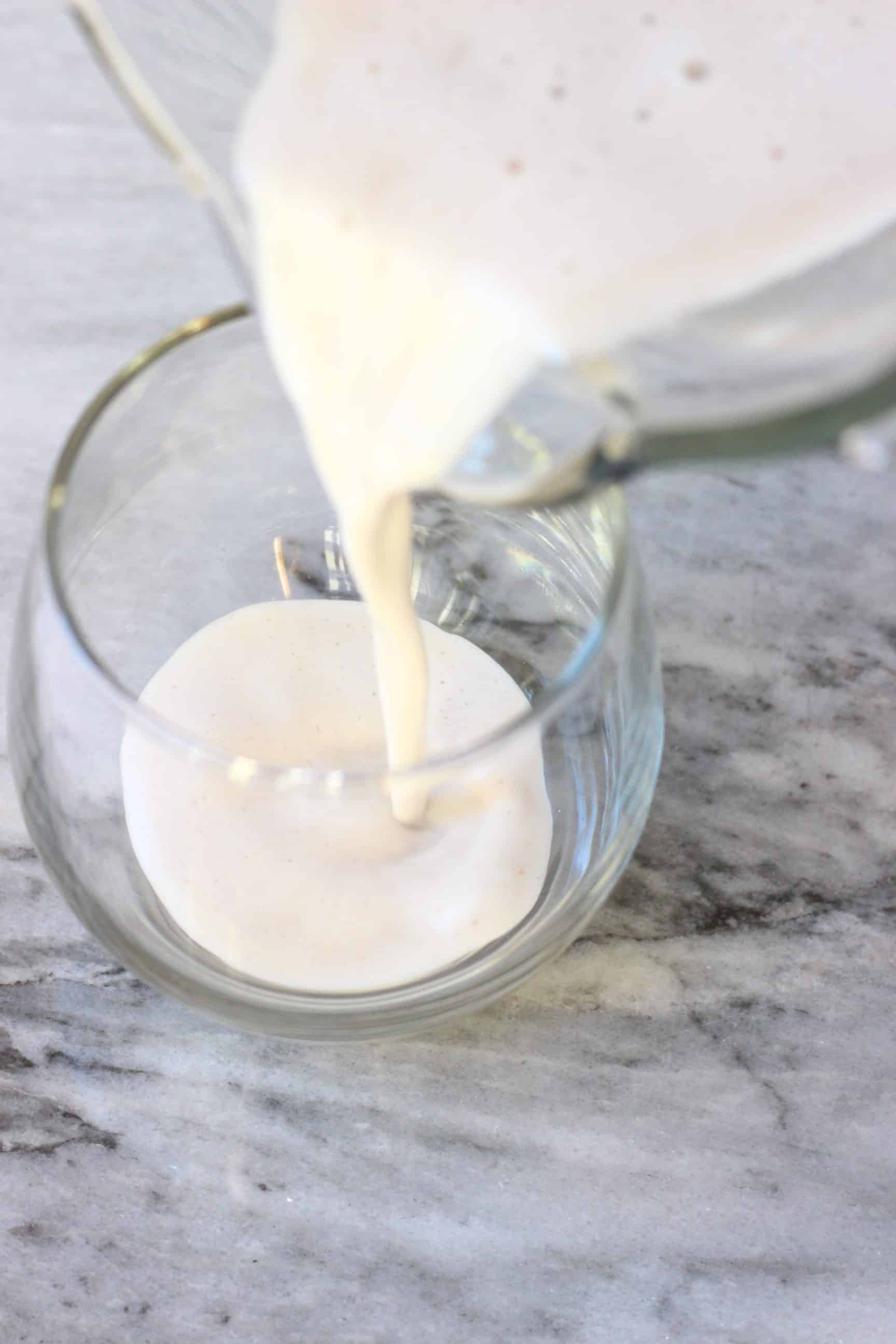 Vegan eggnog being poured into a glass from a blender 