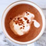 Red wine hot chocolate topped with cream and cocoa powder in a mug