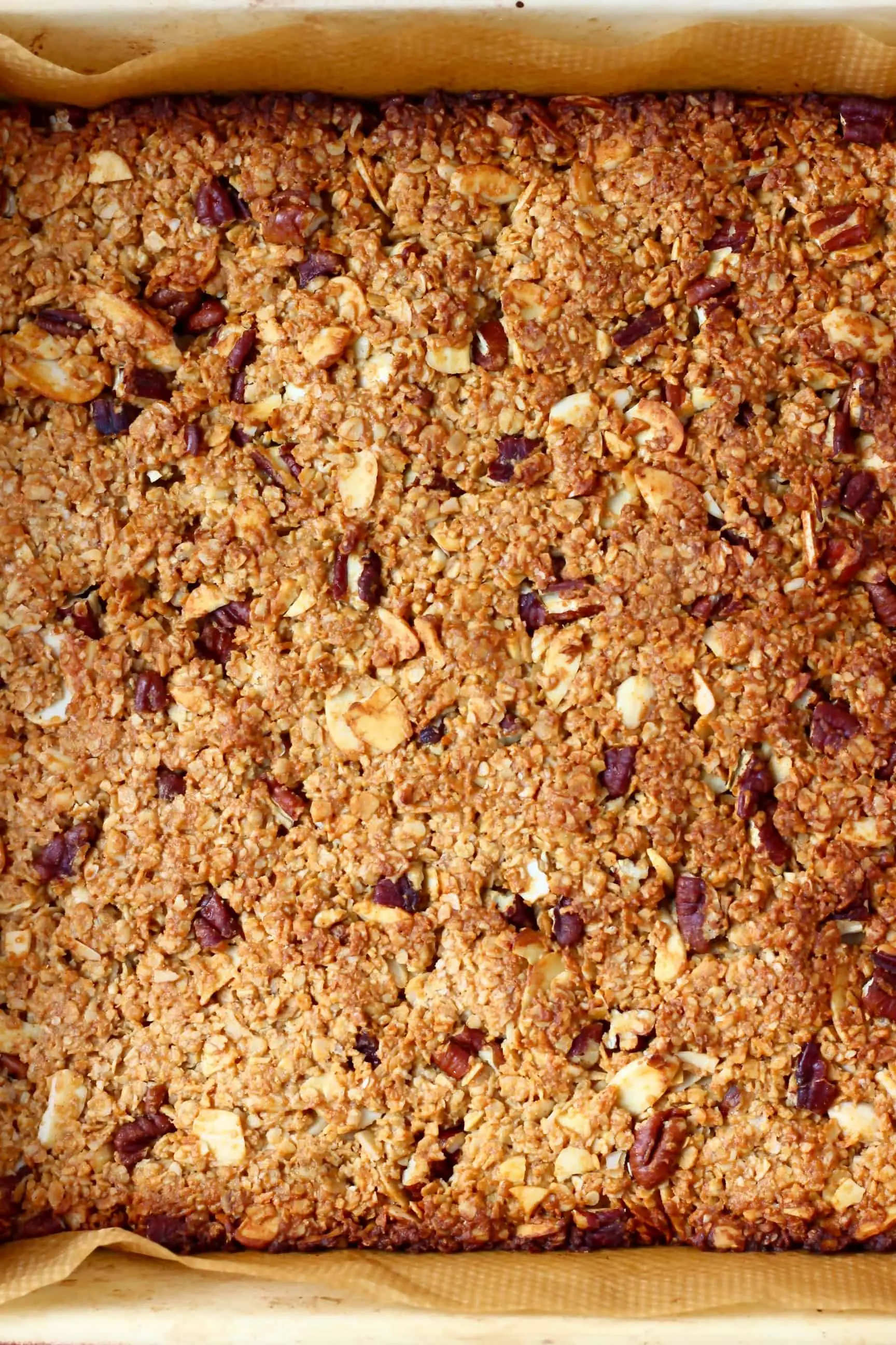 Baked vegan granola bars in a square baking tin lined with baking paper