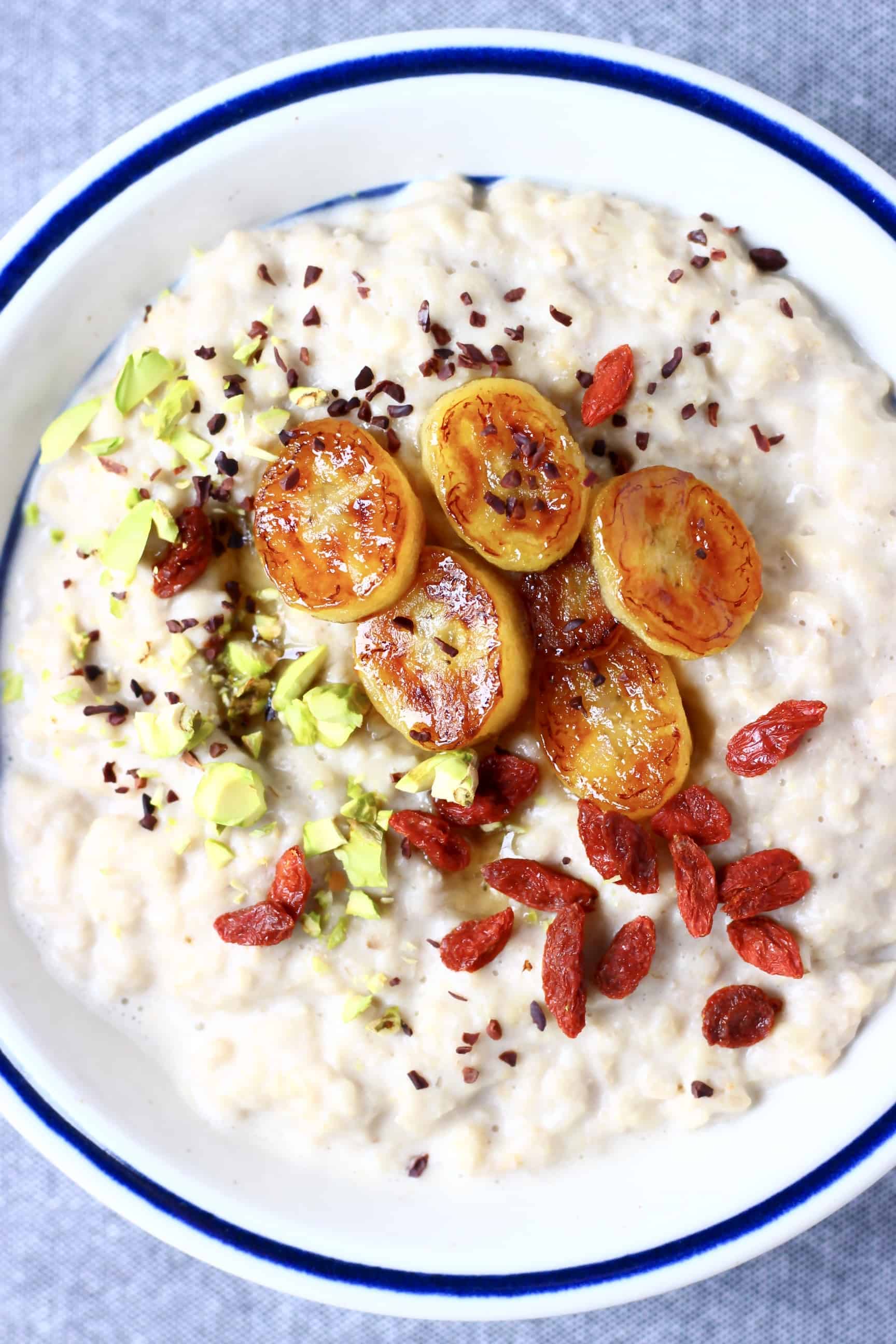 This Vegan Banana Oatmeal is comforting and warming, sweet and creamy and free from added sugar! It makes the perfect filling and nutritious breakfast. Egg-free, dairy-free, refined sugar free, no added sugar and gluten-free. #rhiansrecipes #vegan #glutenfree #dairyfree #breakfast #banana A bowl of vegan banana oatmeal topped with caramelised bananas, goji berries, chopped pistachios and cacao nibs