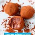 Three chocolate truffles on a blue plate one with a bite taken out of it