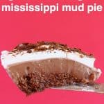 A slice of chocolate pie topped with whipped cream and chocolate shavings being held up against a bright pink background
