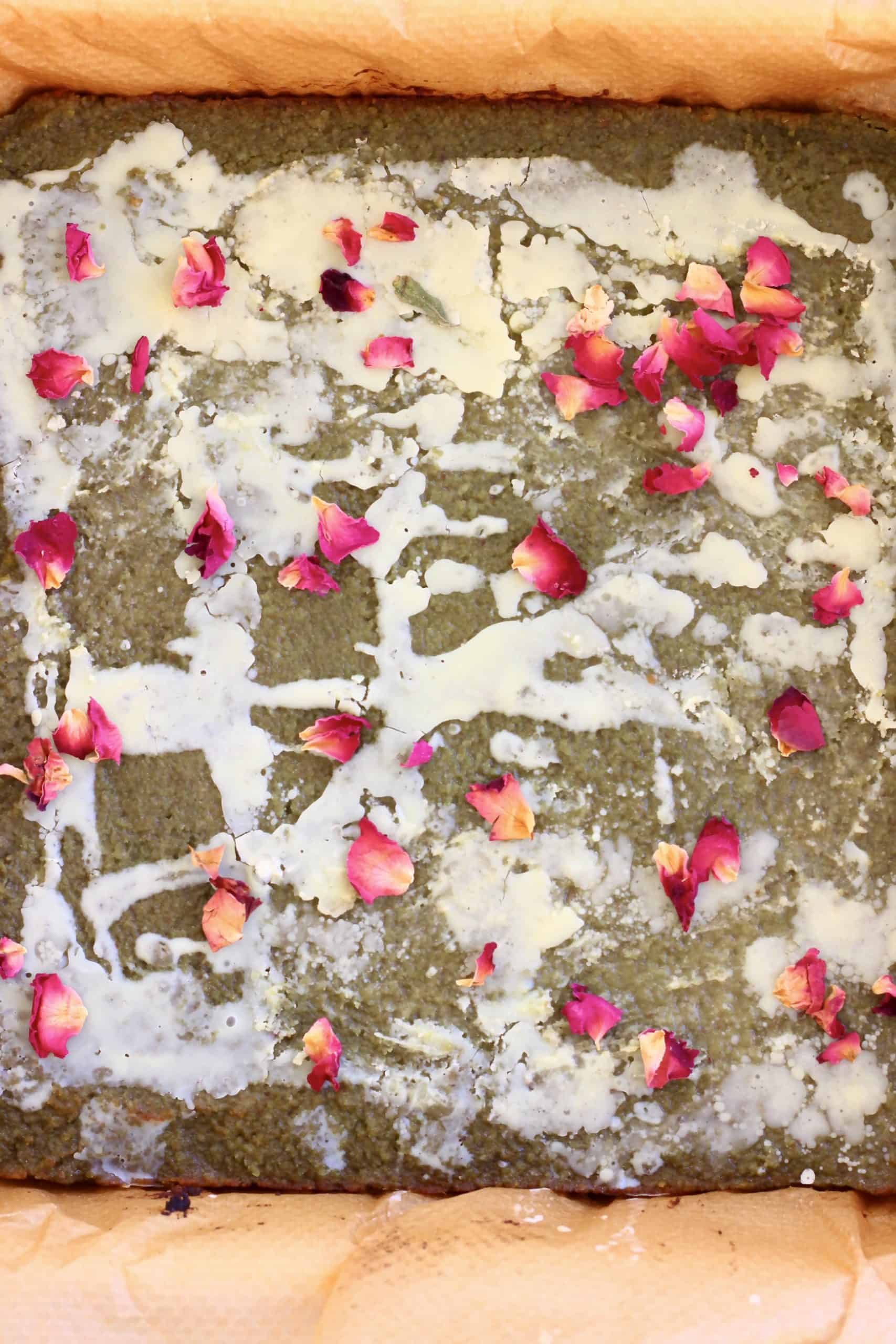 Gluten-free vegan matcha brownies drizzled with white chocolate glaze and decorated with rose petals