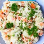 Potato salad with carrots, green peas and mayonnaise in a blue bowl against a marble background