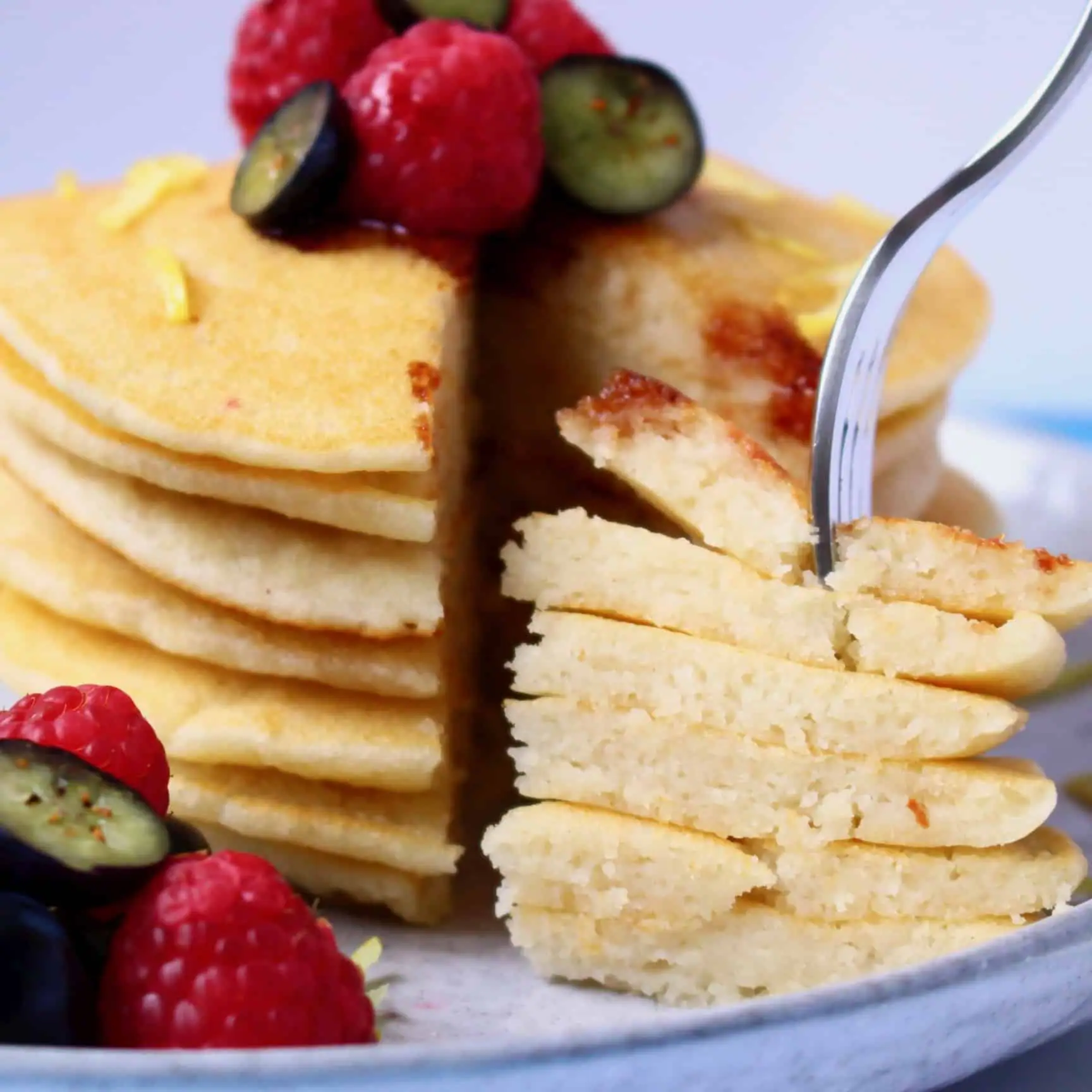 A stack of gluten-free vegan pancakes with a fork sticking into a slice of them