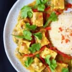 Peanut tofu satay curry with green beans and red peppers on a plate with brown rice