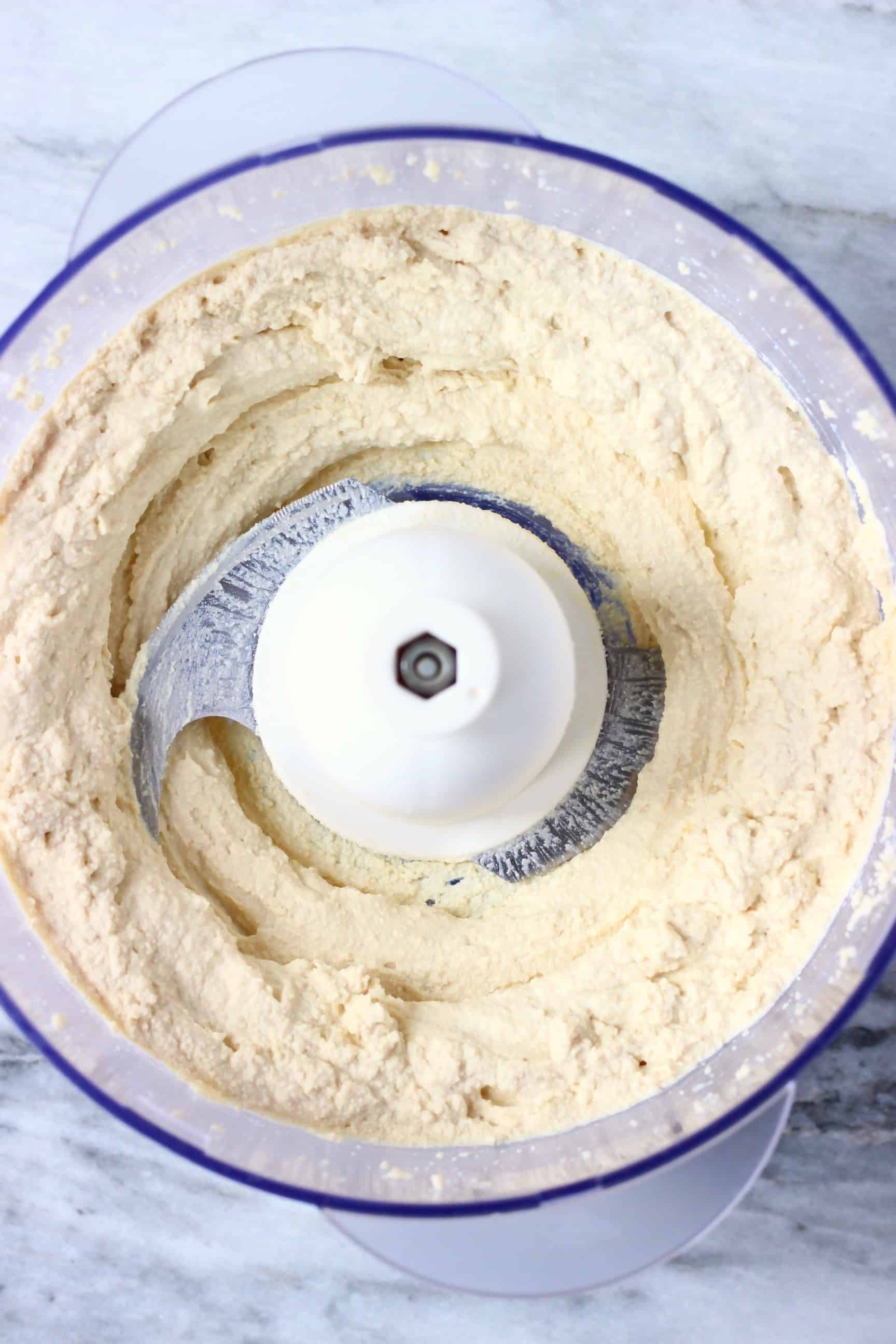 Blended up tofu in a food processor against a marble background