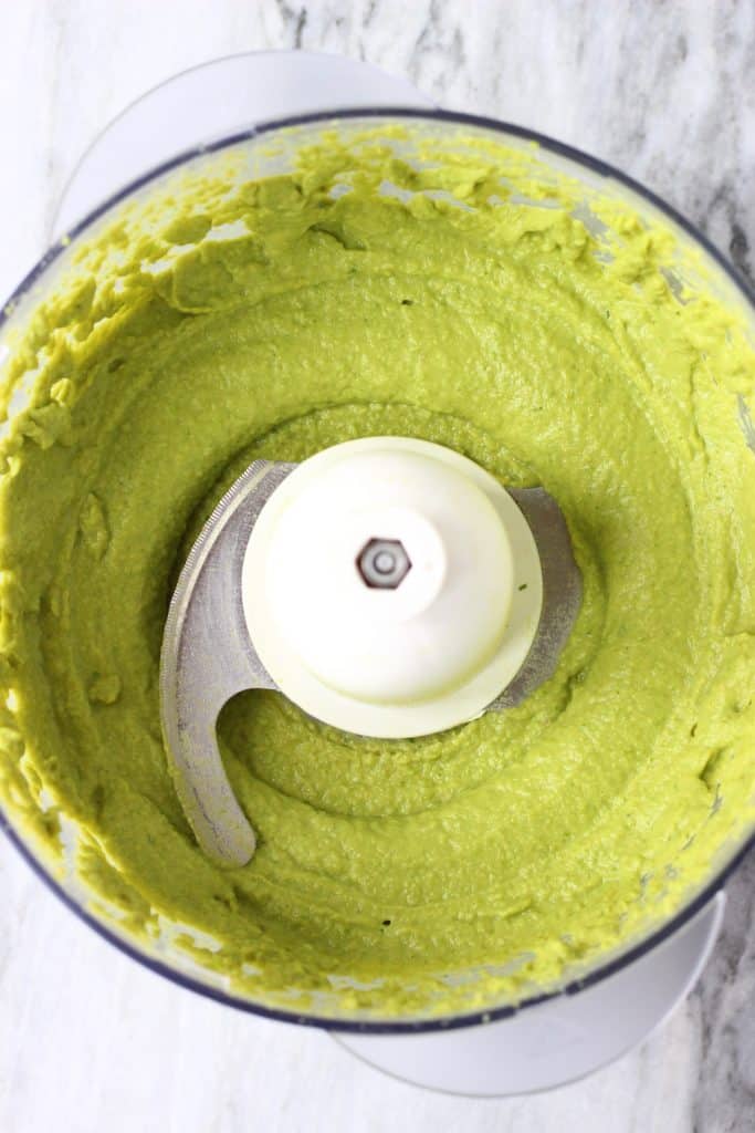 Edamame pesto in a food processor against a marble background
