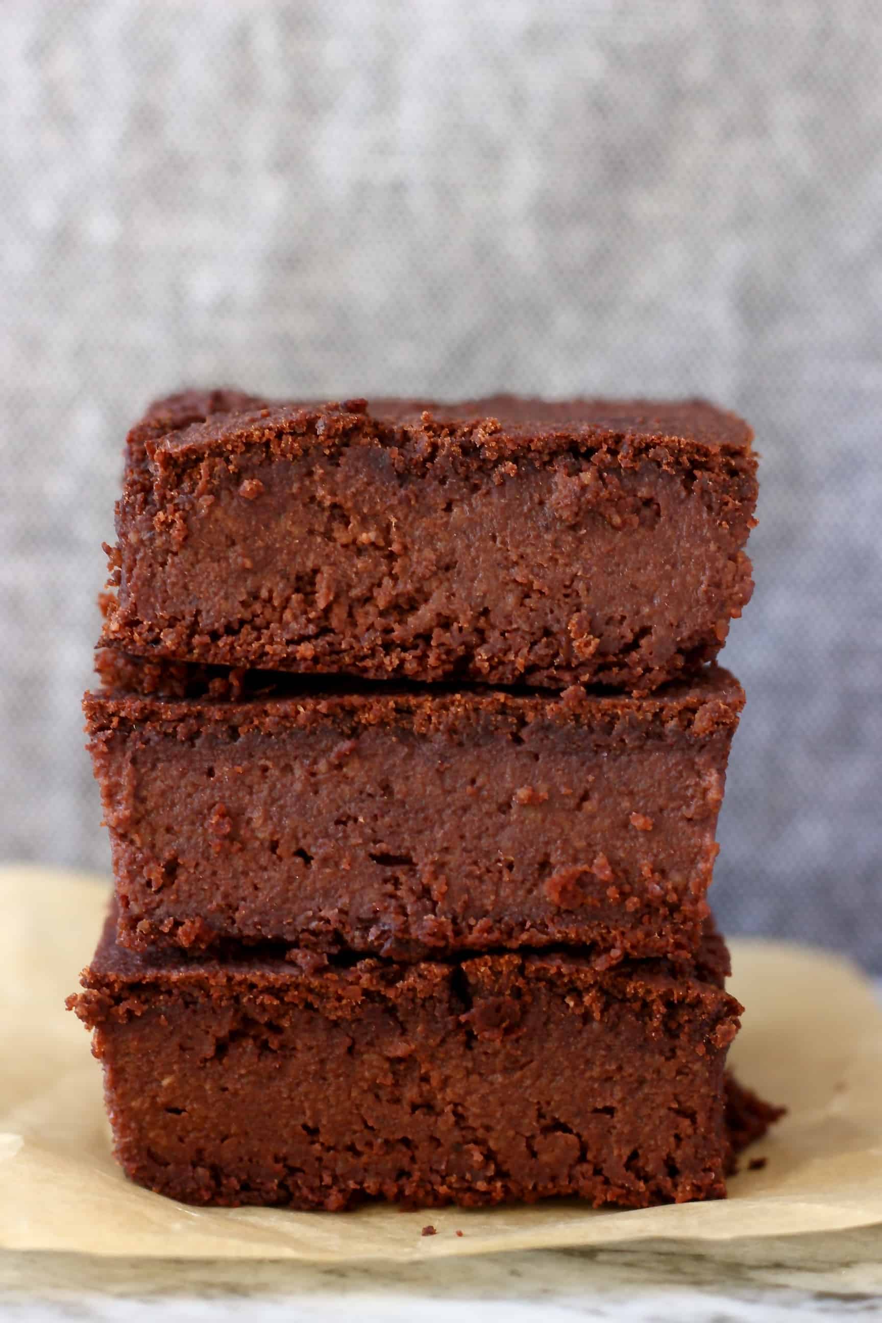 Three vegan black bean brownies stacked on top of each other against a grey background