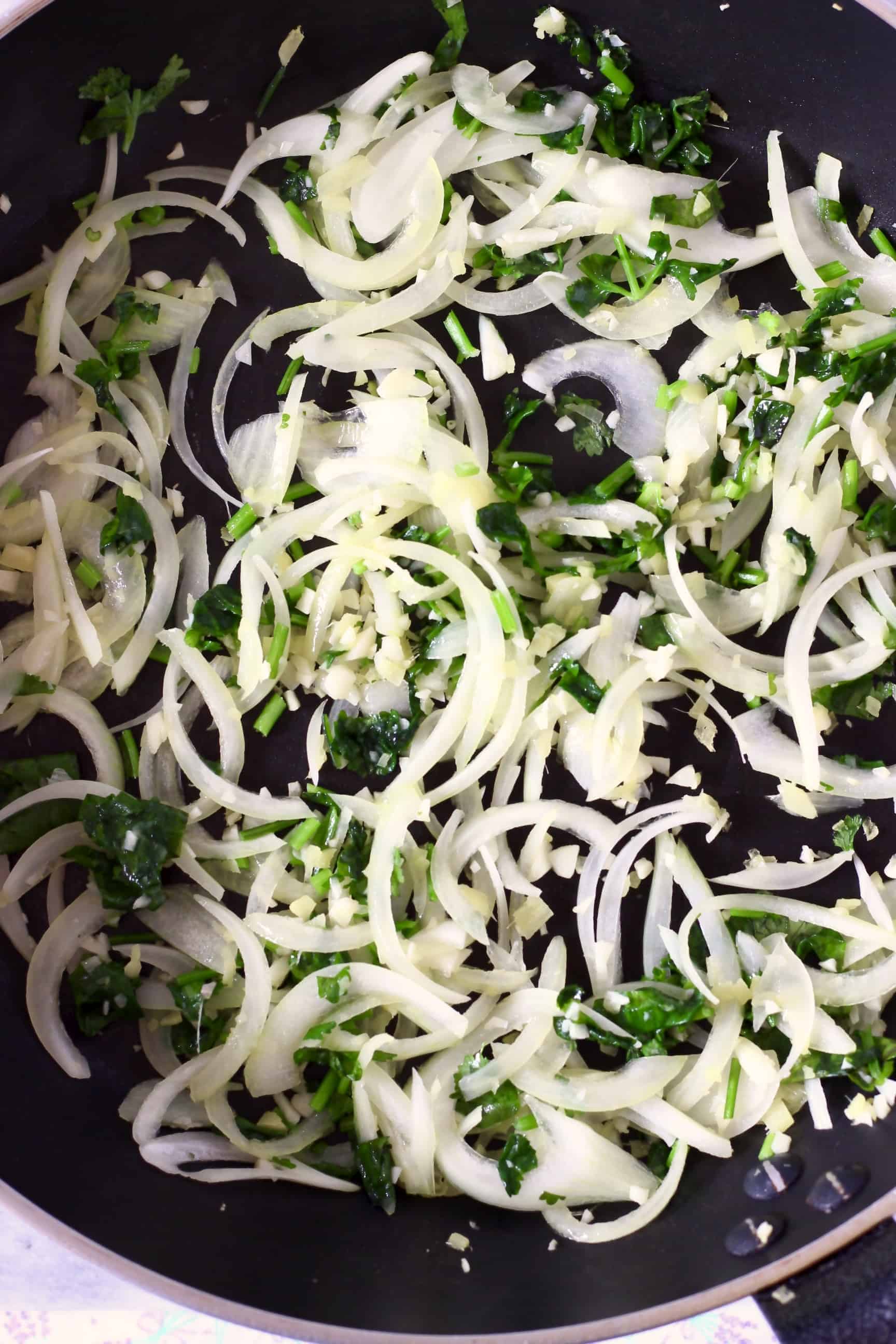 Sliced onion, minced garlic, minced ginger and chopped coriander in a frying pan