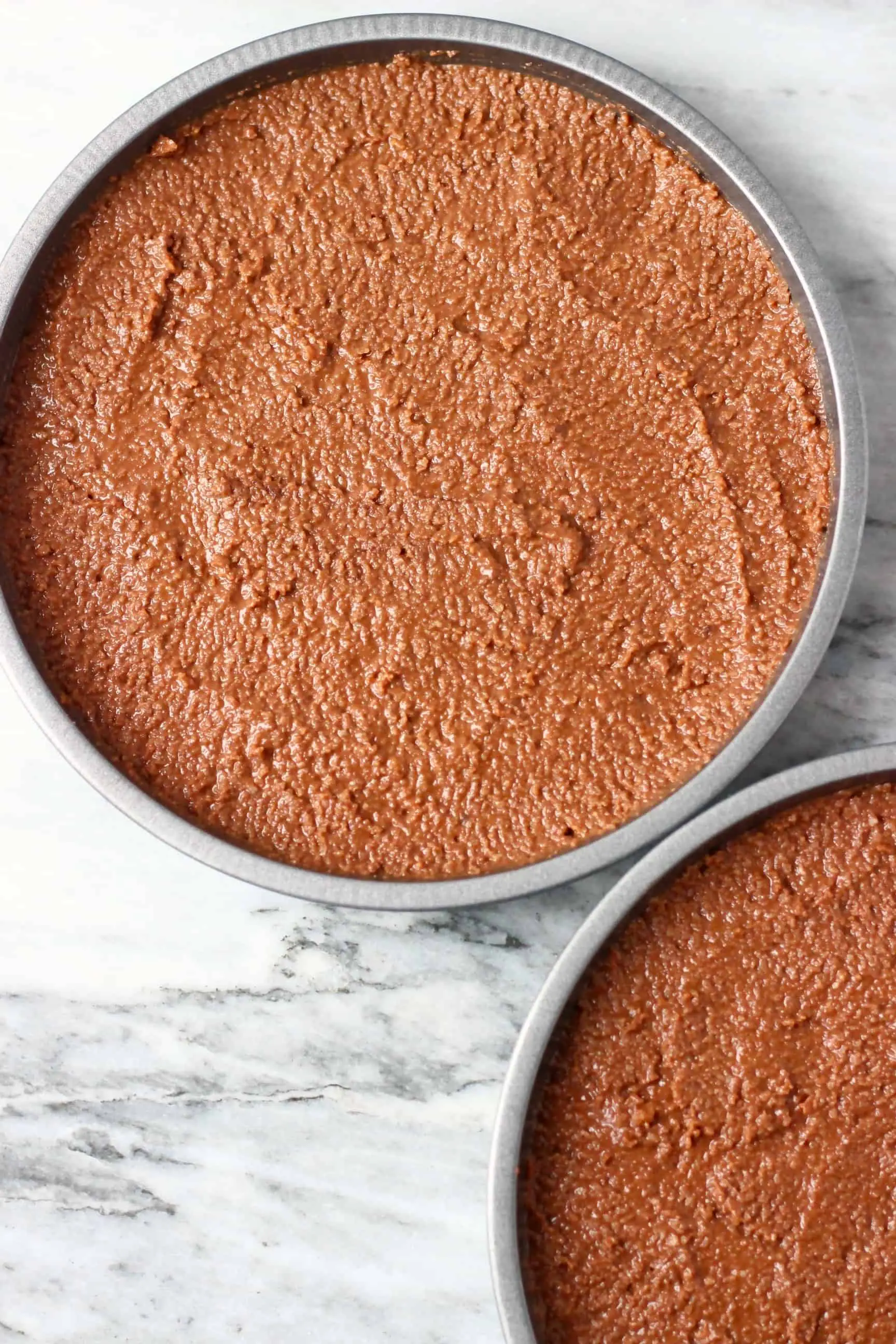 Two round baking tins filled with gluten-free vegan chocolate cake batter 