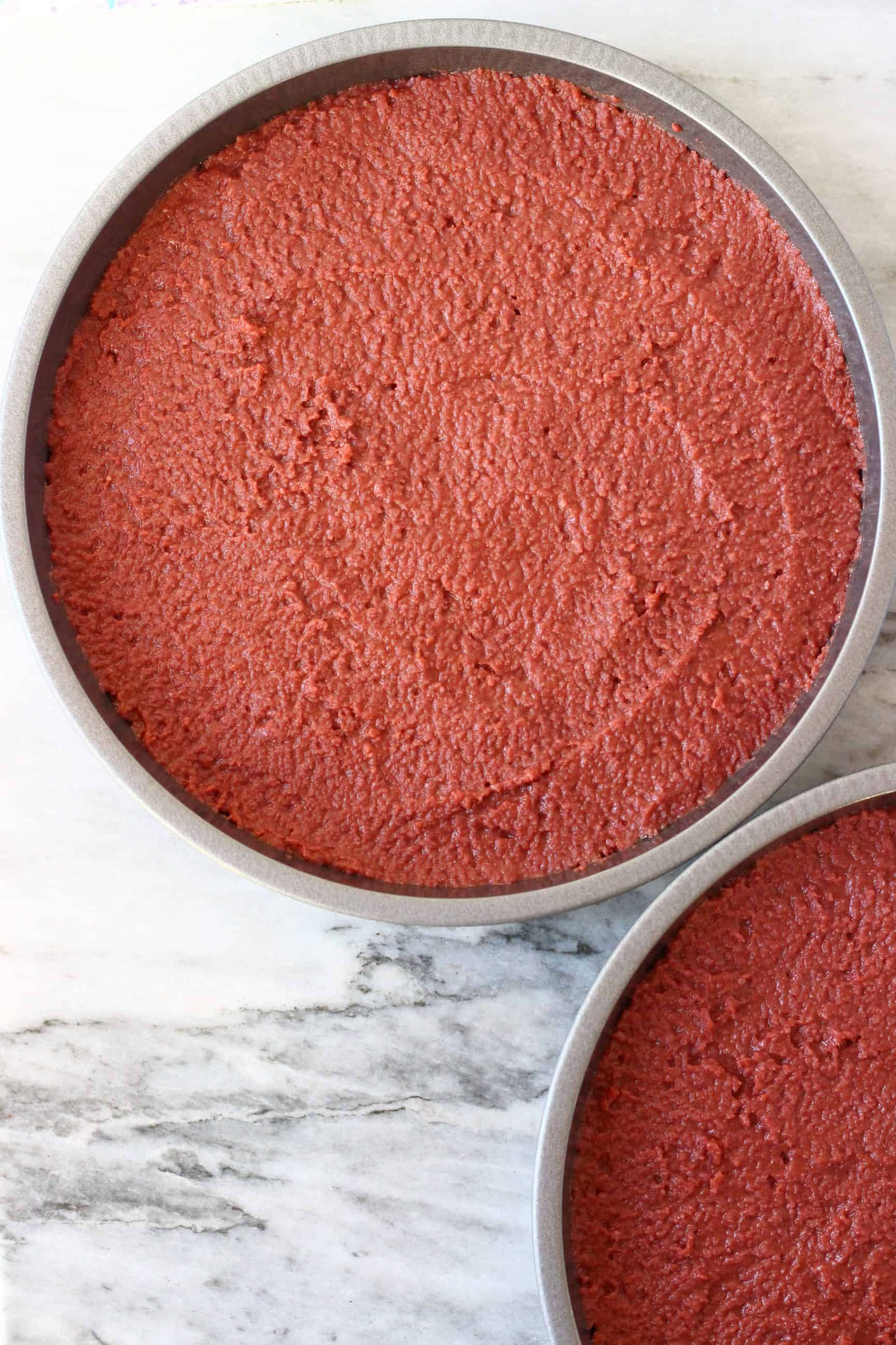 Raw gluten-free vegan red velvet cake batter in two circular baking tins