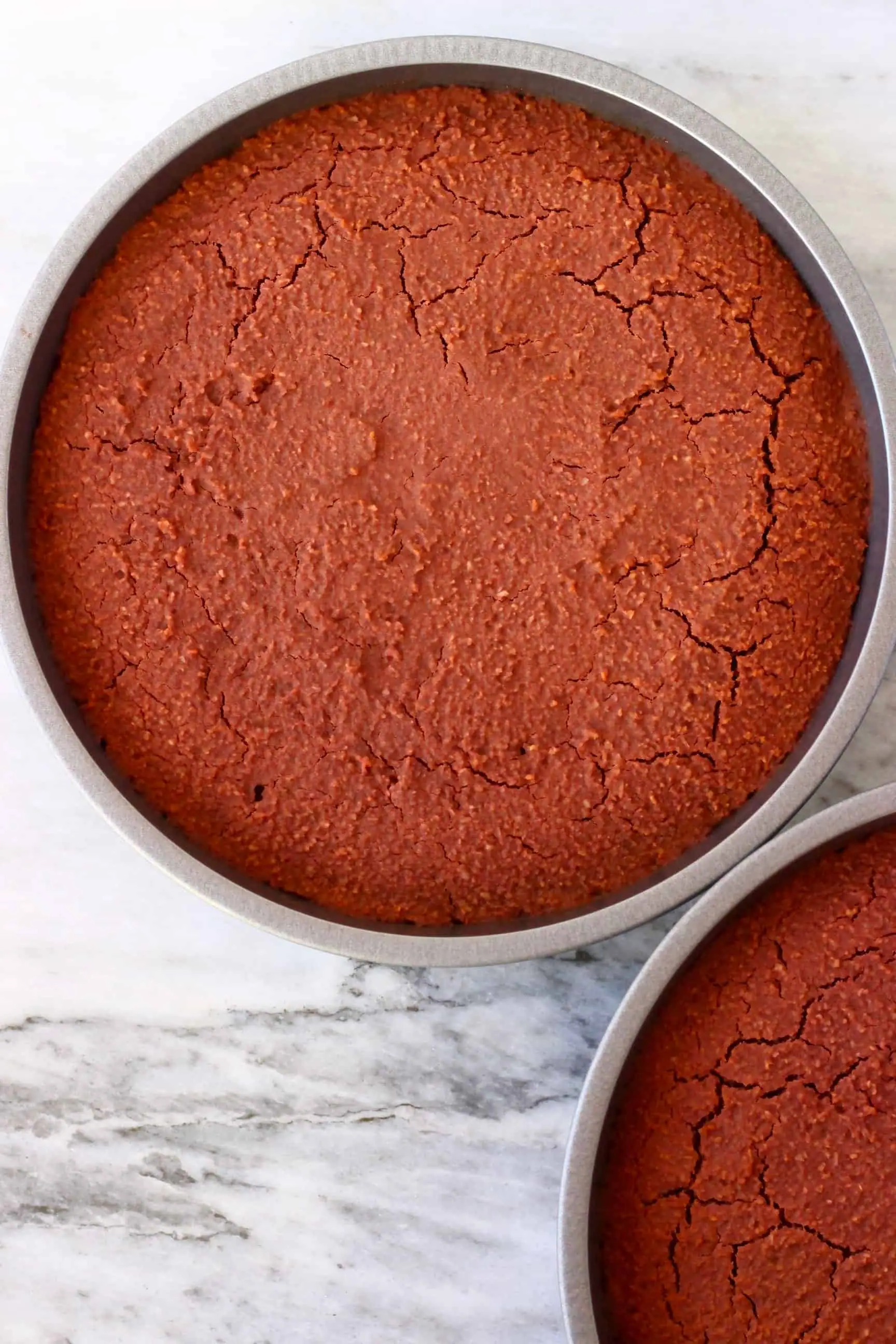 Two gluten-free vegan red velvet cake sponges in circular baking tins 