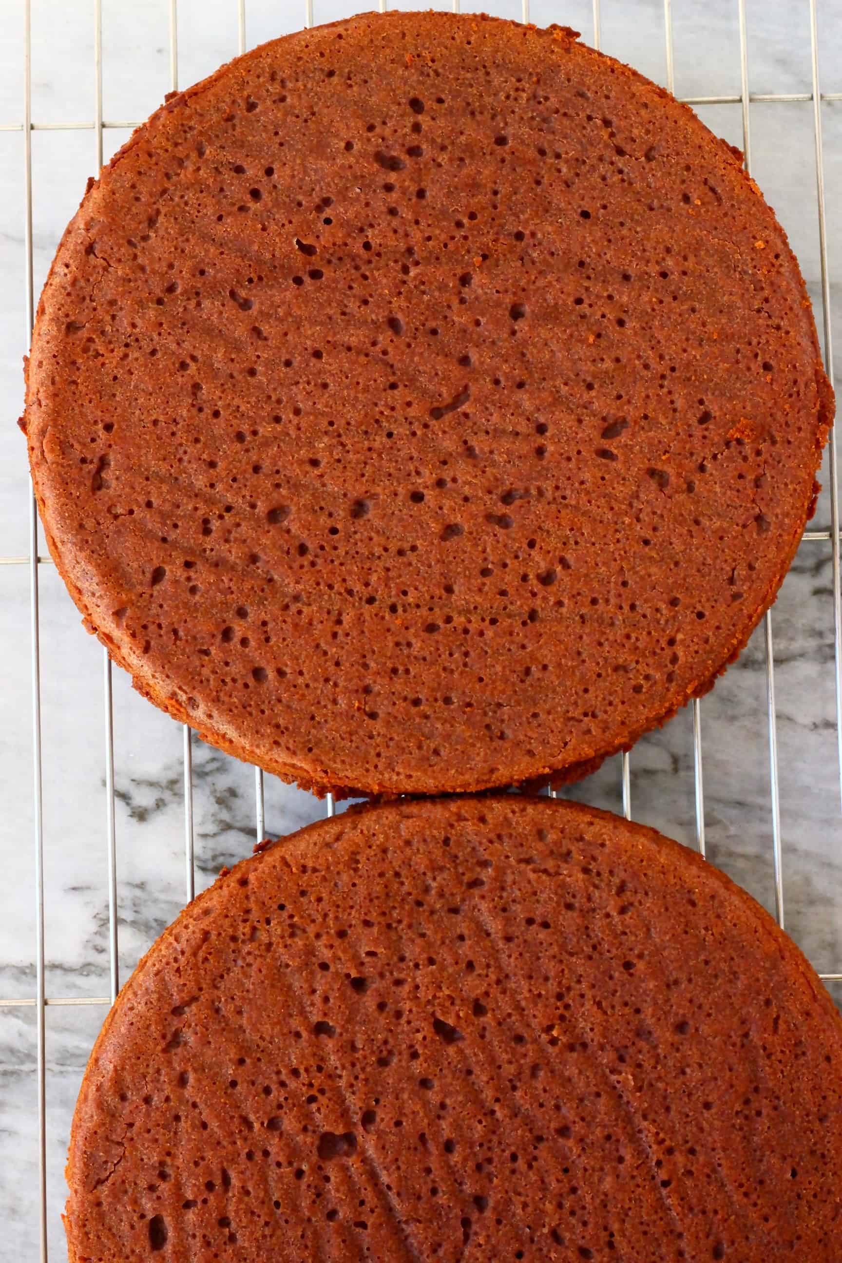 Two gluten-free vegan red velvet cake sponges on a silver wire rack 