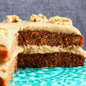 A sliced gluten-free vegan coffee cake with coffee frosting and walnuts on a cake stand