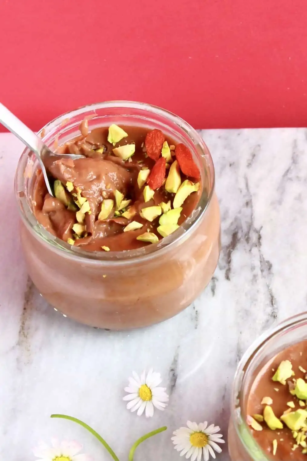 A vegan chocolate pudding pot with a spoon taking out a mouthful