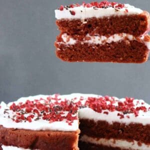 A gluten-free vegan red velvet cake with a slice being lifted up