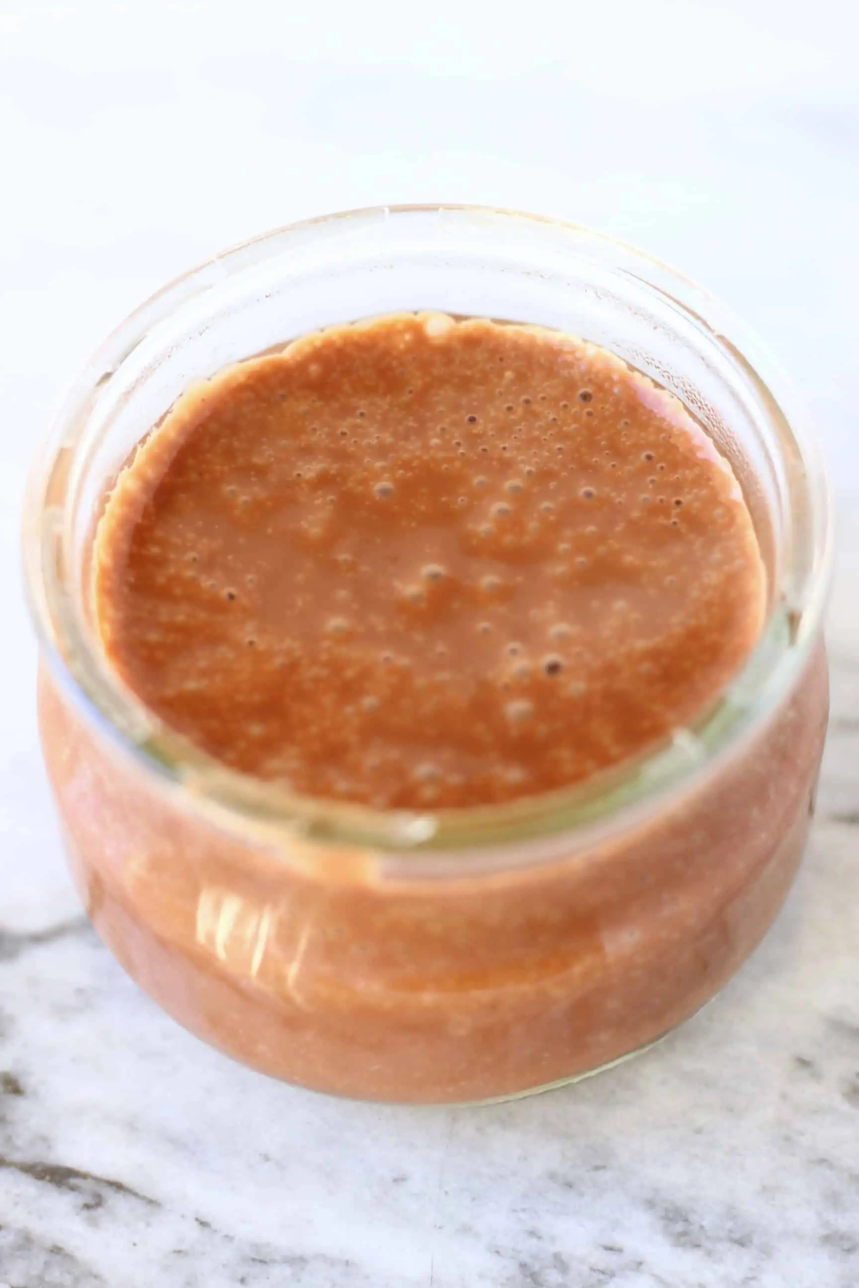 Runny vegan chocolate pudding mixture in a glass pot 