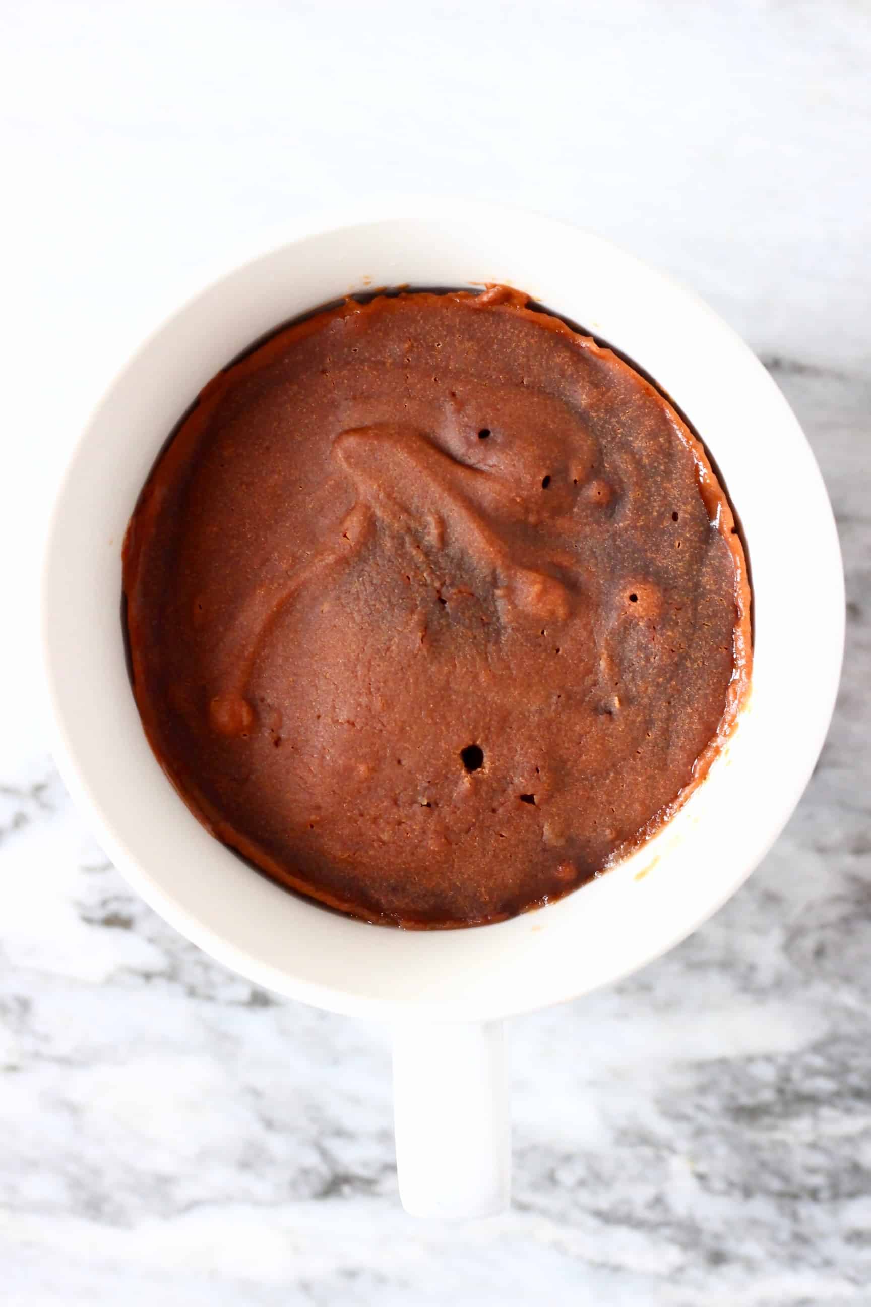 Vegan chocolate mug cake in a white mug against a marble background