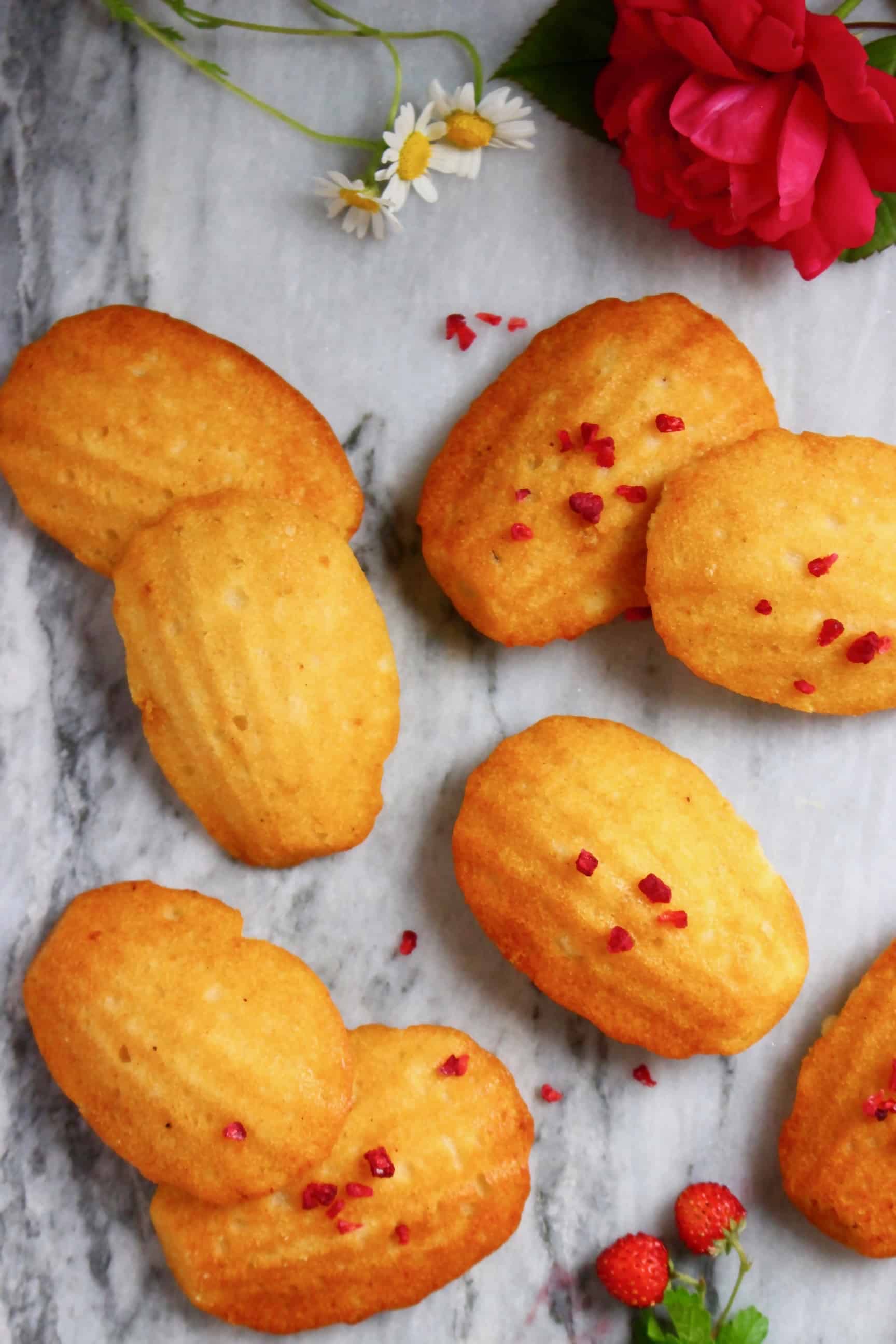 Seven gluten-free vegan madeleines on a marble background decorated with flowers