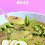 Green soup topped with green vegetables in a light blue bowl against a pink background with a silver spoon lifting up a mouthful