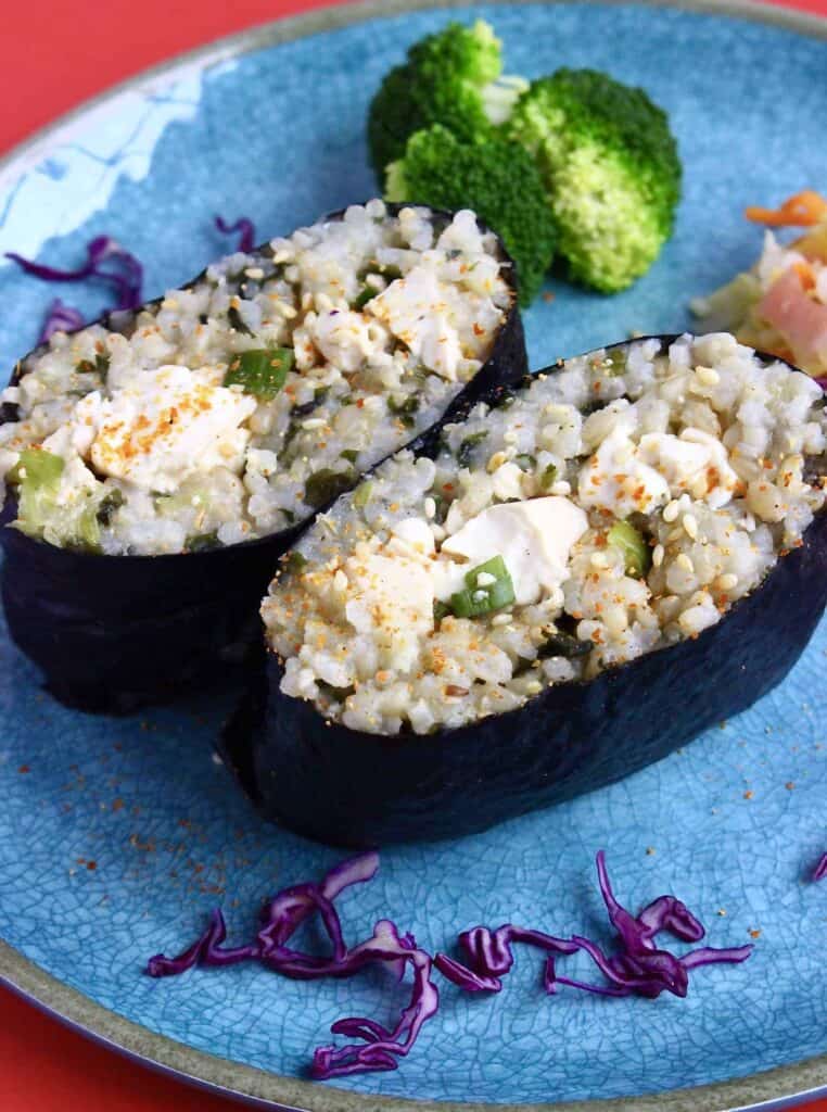 Two onigirazu filled with scrambled tofu on a blue plate against a red background