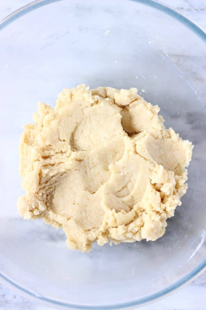 Pastry dough in a glass mixing bowl against a marble background
