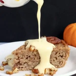 A slice of gluten-free vegan apple cake on a plate with custard being poured on top
