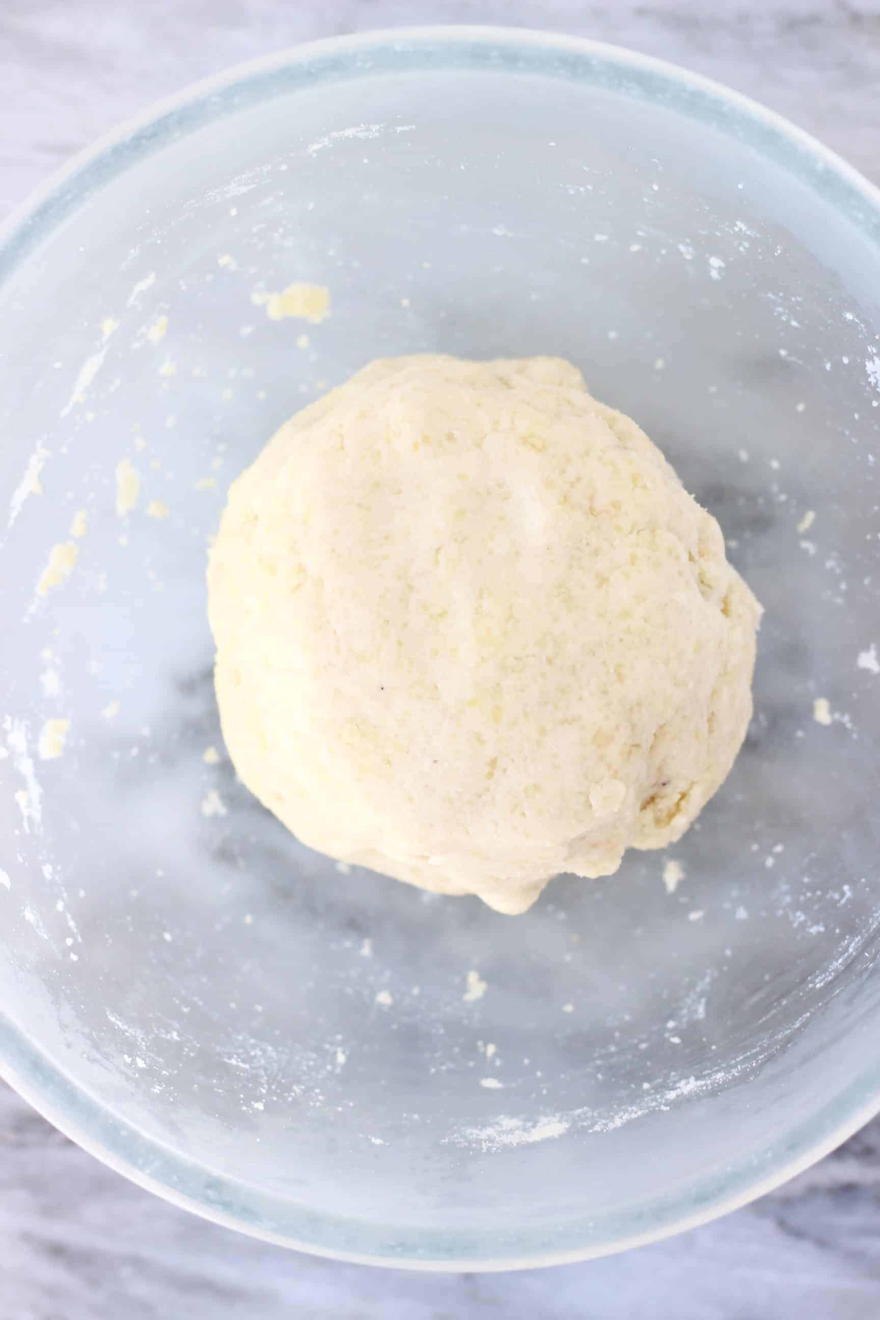 Gluten-free vegan pastry dough in a glass mixing bowl against a marble background