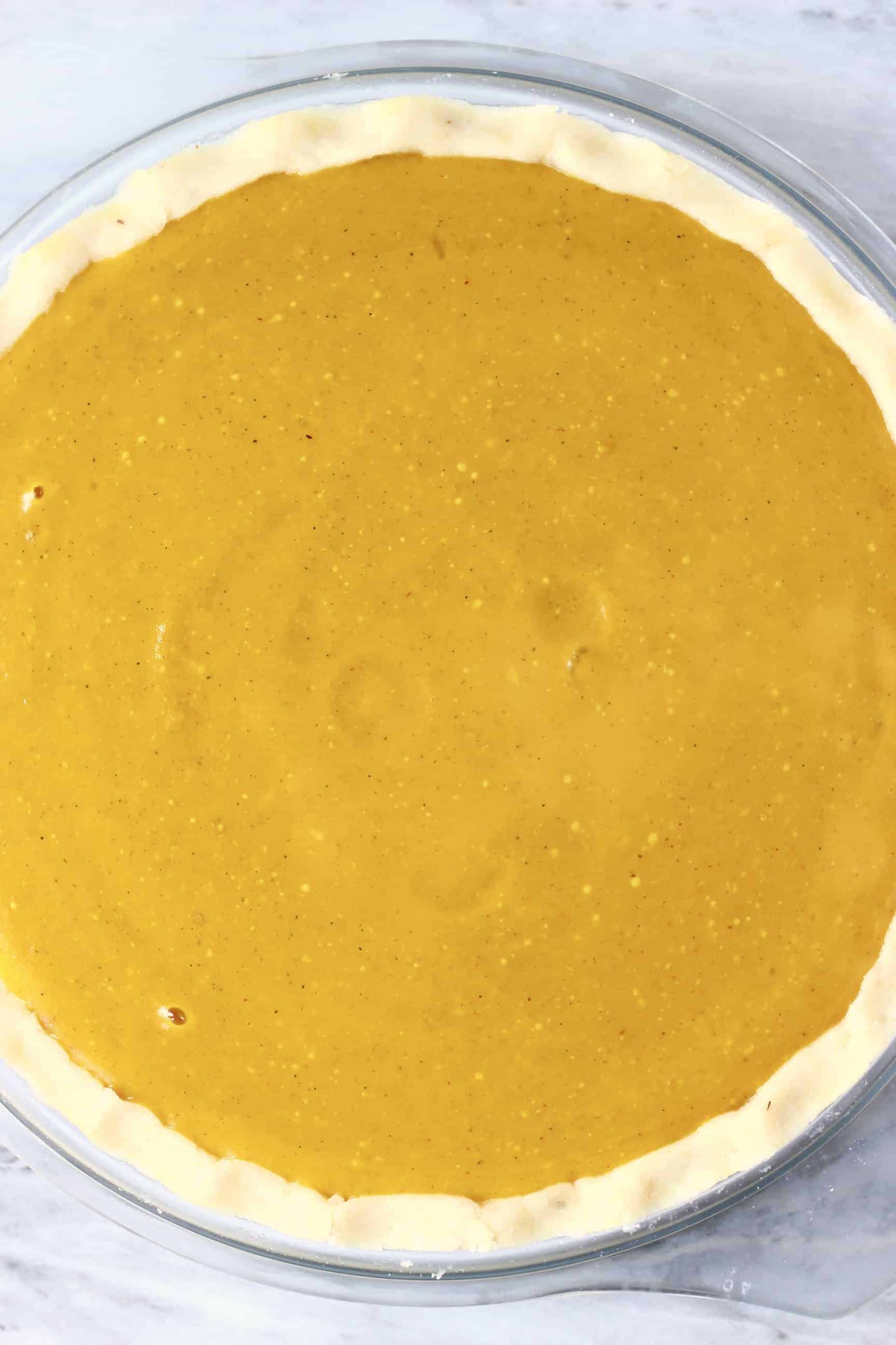 This Gluten-Free Vegan Pumpkin Pie is perfectly spiced, rich and creamy, and flaky, crispy and buttery. The perfect dessert for autumn/fall, Thanksgiving and Christmas. Egg-free, dairy-free and refined sugar free. #vegan #rhiansrecipes #dairyfree #glutenfree #pie #pumpkin #thanksgiving A raw gluten-free vegan pumpkin pie with pumpkin pie filling in a pie dish