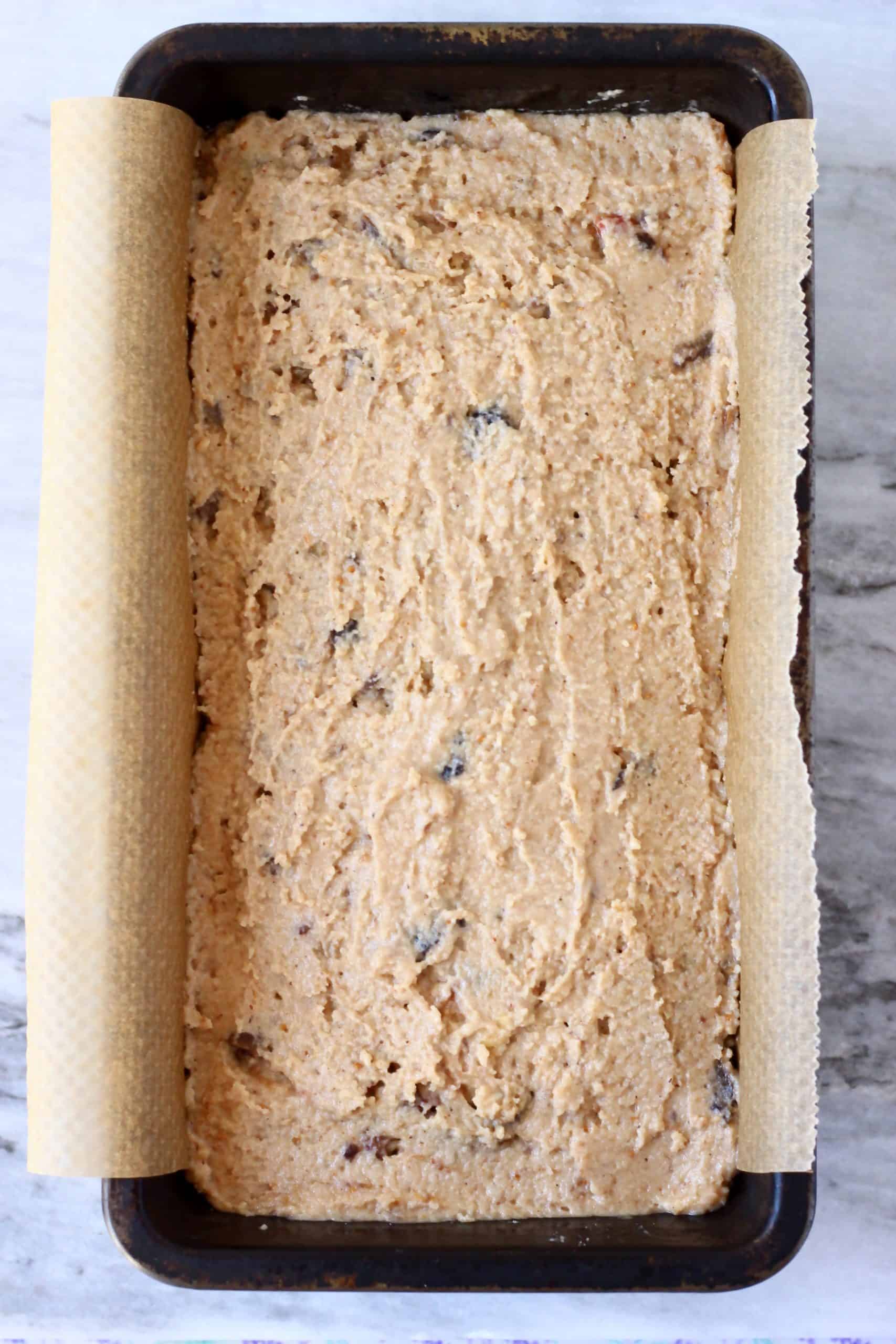 Raw gluten-free vegan fruit cake batter in a loaf tin lined with baking paper