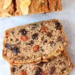A gluten-free vegan fruit cake with two slices next to it