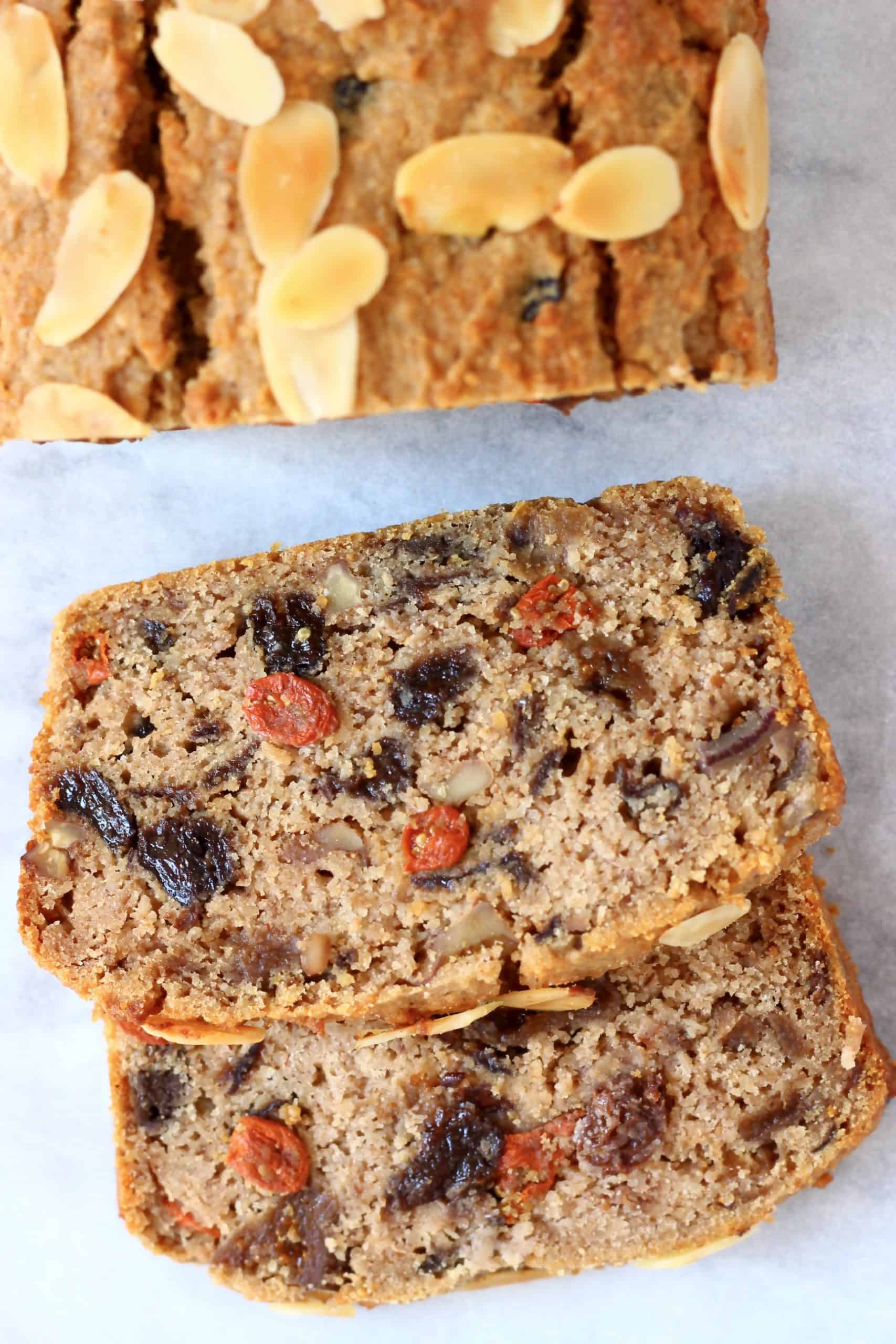 A gluten-free vegan fruit cake with two slices next to it